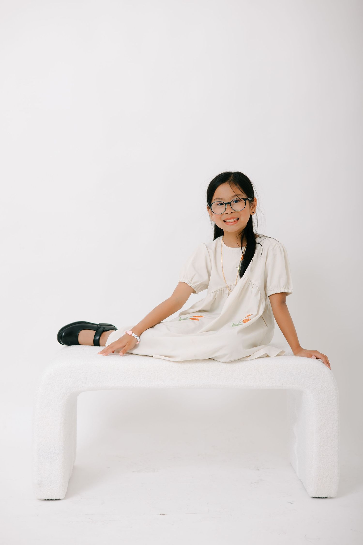 Person in white outfit lounges gracefully on minimalist white platform against clean white background.
