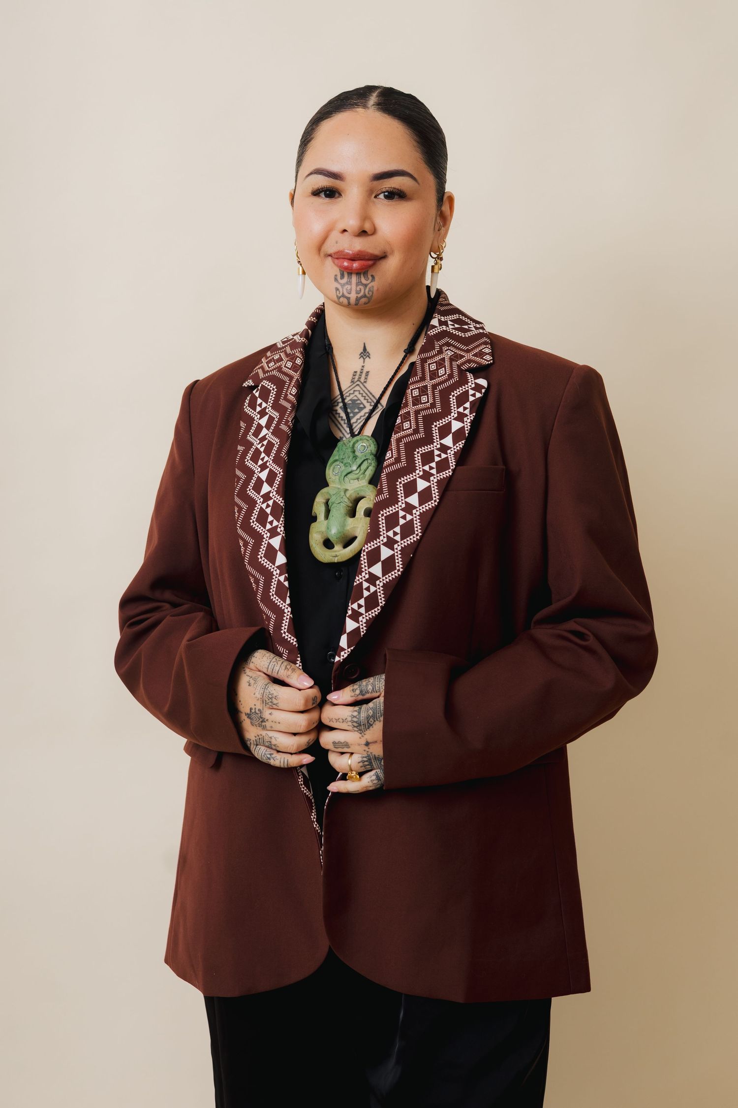 A person in a brown blazer with patterned lapels and green jewelry poses against a beige background in multiple shots.