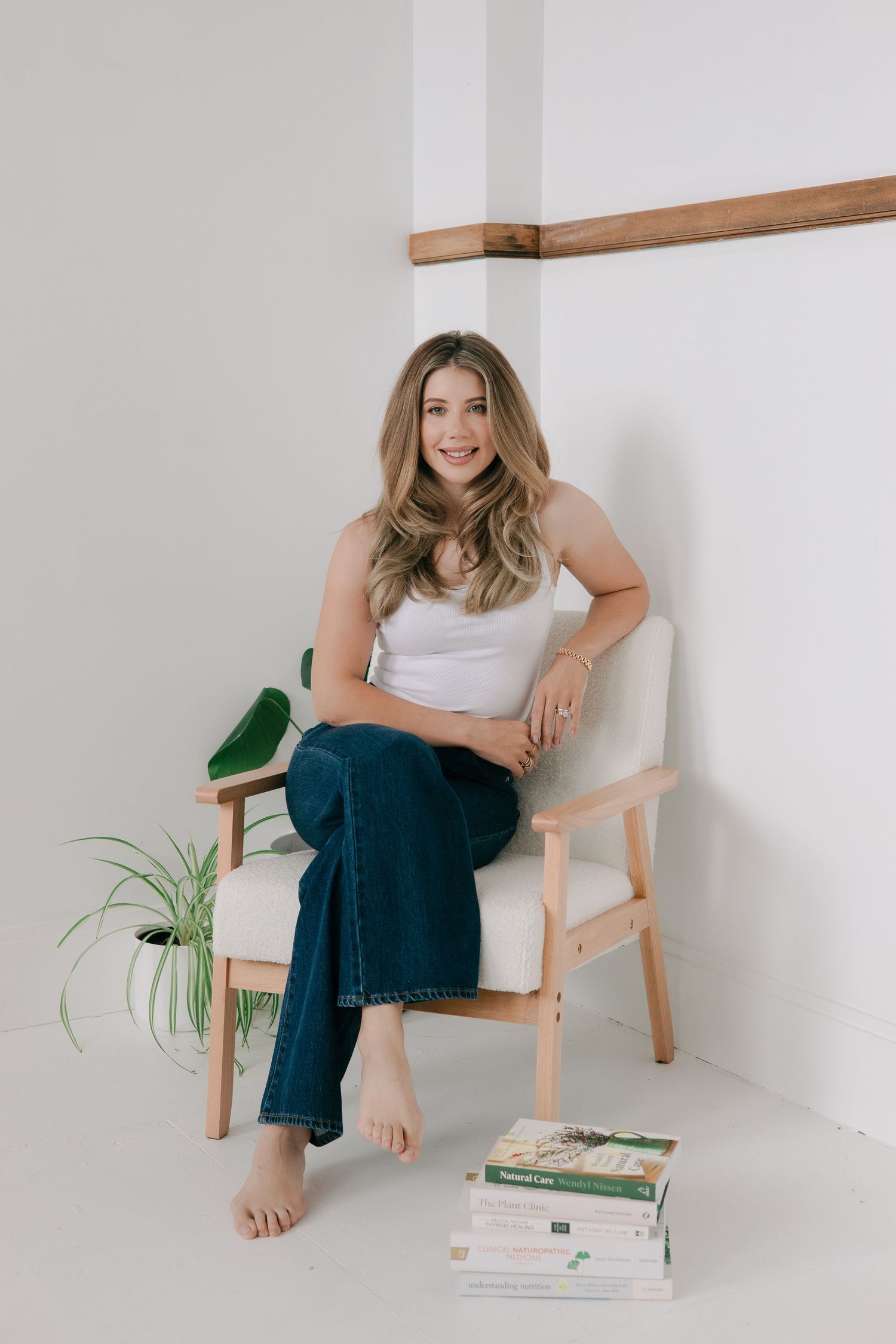 Minimalist lifestyle photo series showing relaxed poses in a wooden chair with books and plants against white wall.
