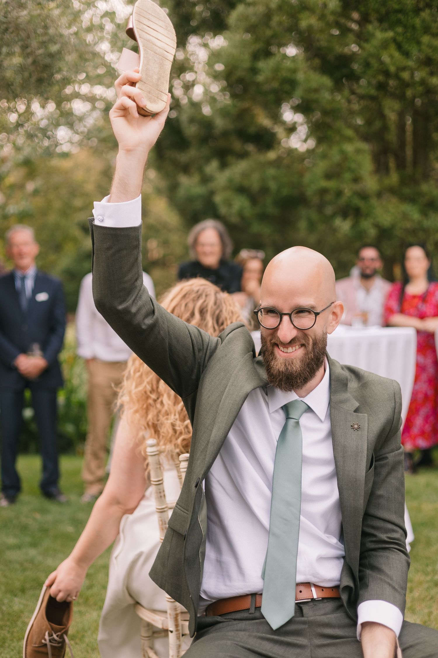 Joyful wedding celebration with guests dancing on lawn during outdoor reception.