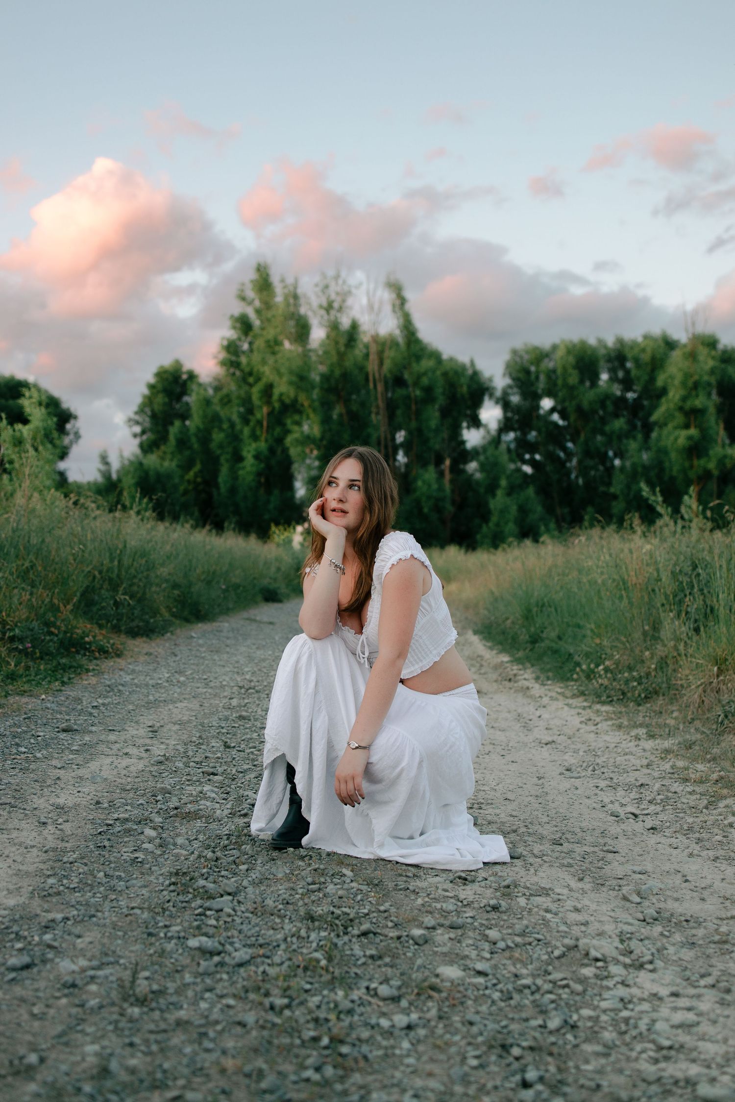 A series of artistic photos showing someone in white dress sitting on a dirt path at sunset with trees in background.