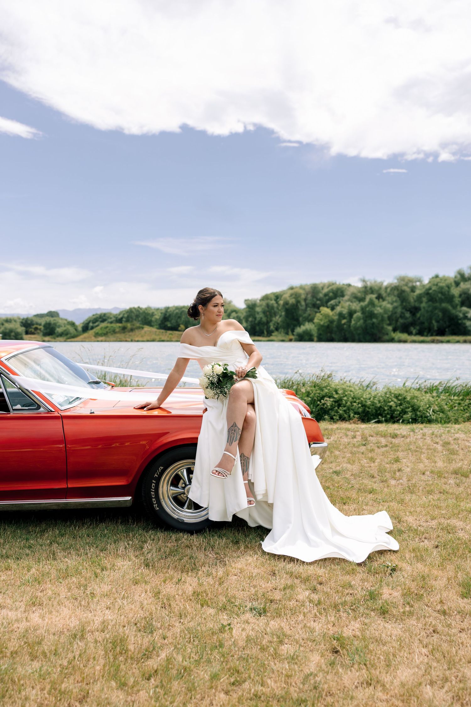 A sequence of romantic wedding photos showing a couple posing with a classic red convertible car in a grassy field.