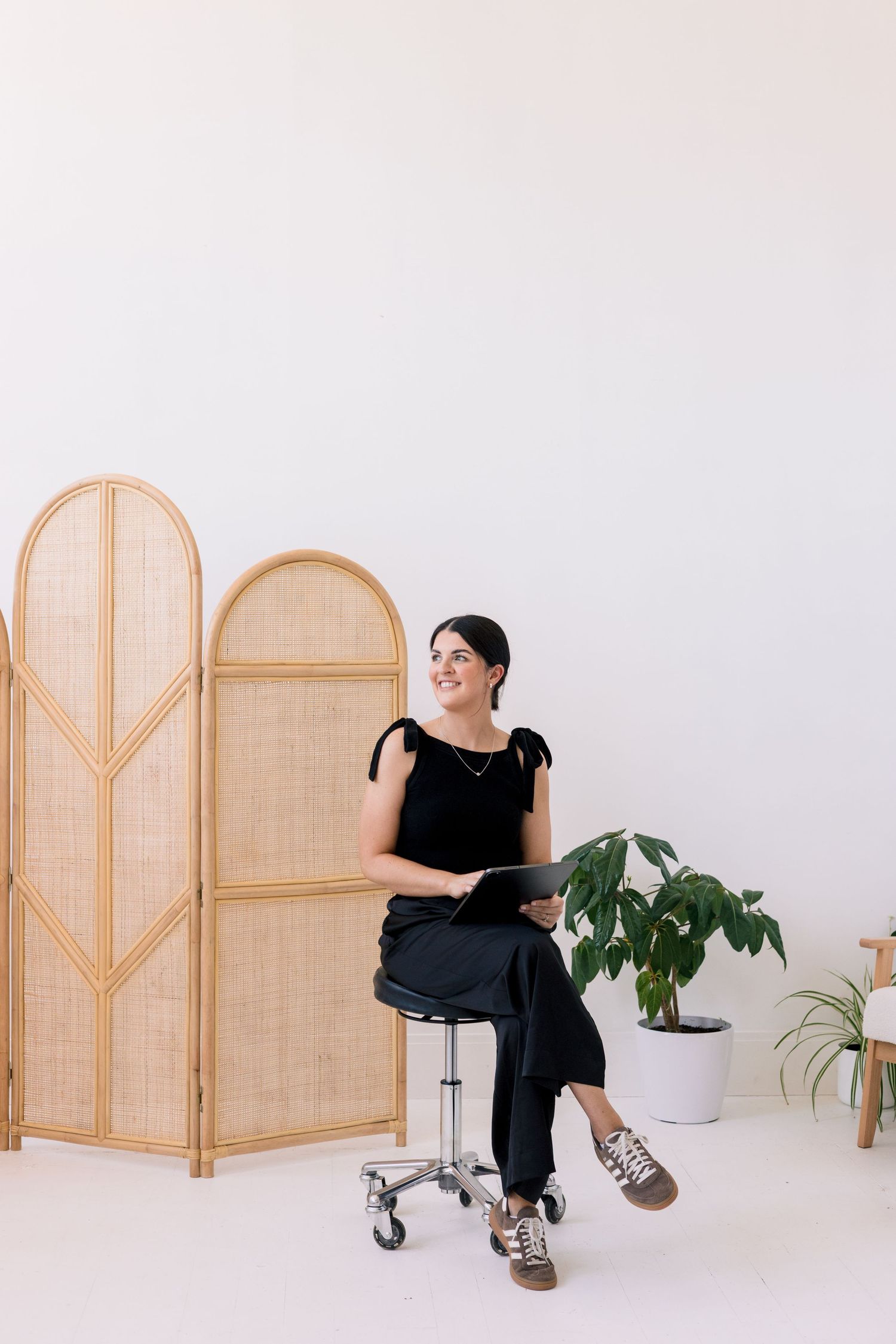 Four minimalist photos show someone sitting near a rattan room divider screen against a white background.