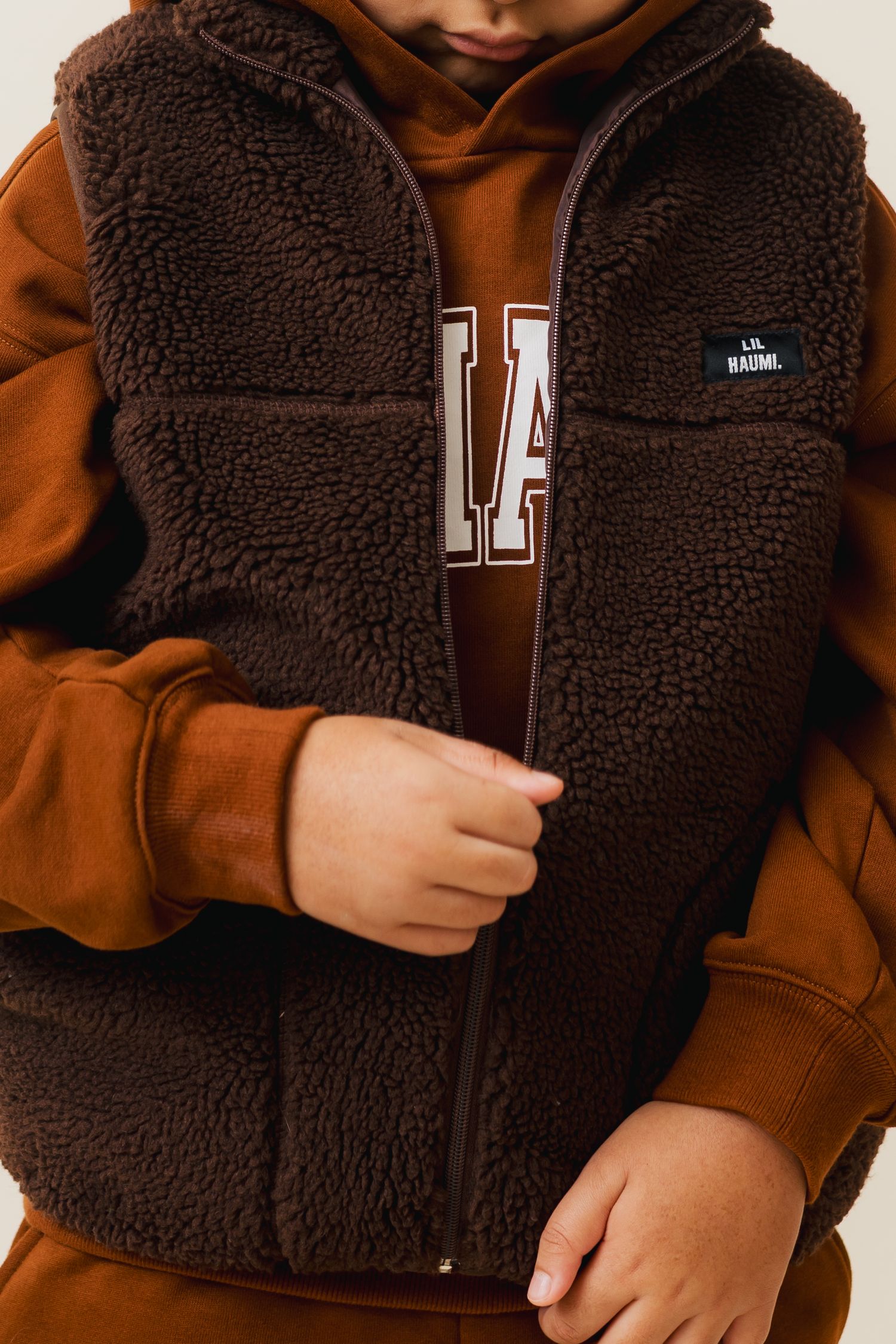Close-up shots of a cozy brown and black sherpa fleece jacket showing texture and zipper details.