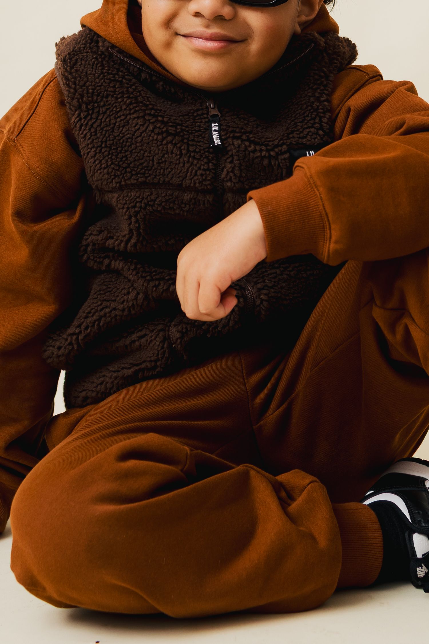 A recurring collage of a brown hooded fleece sweater showing various details and angles of the garment.