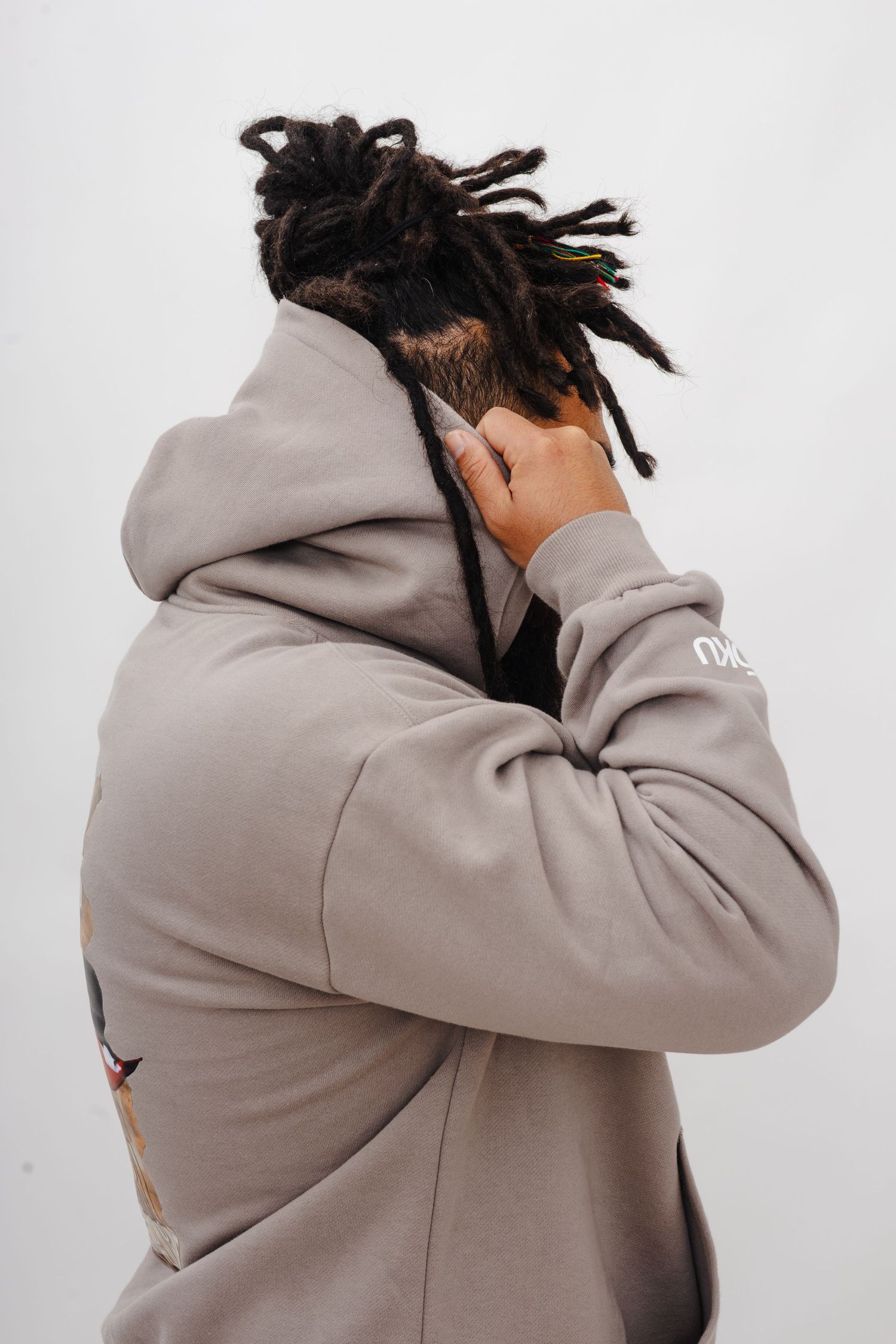 Side profile shot of a person in a light gray hoodie with dreadlocks.