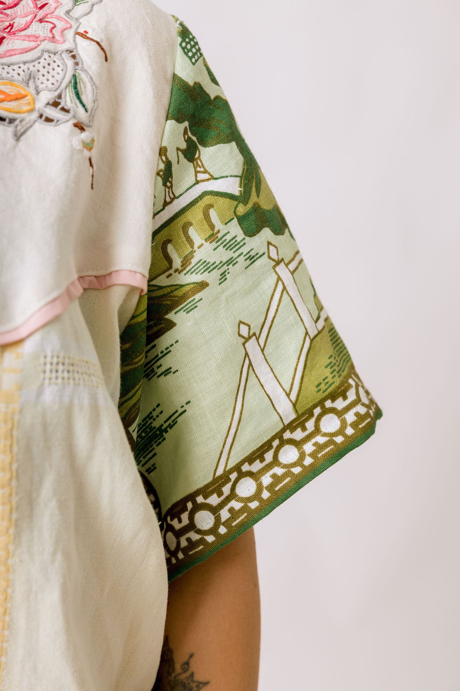 Close-up detail of a white and sage green patterned fabric with decorative design elements showing texture and draping.