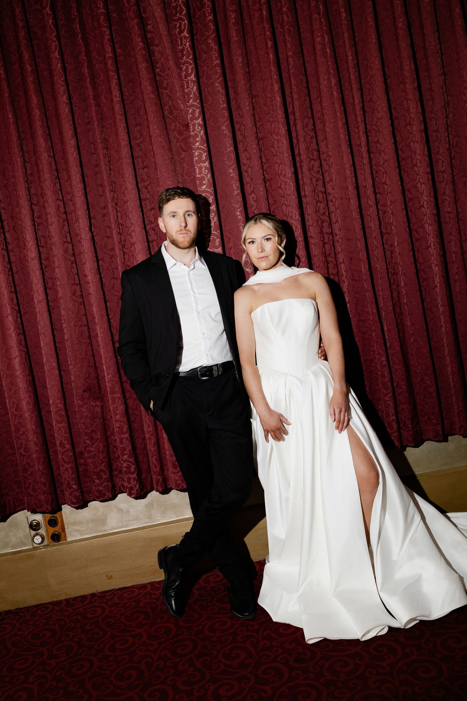 Wedding couple poses dramatically against deep red curtains in a series of artistic shots.