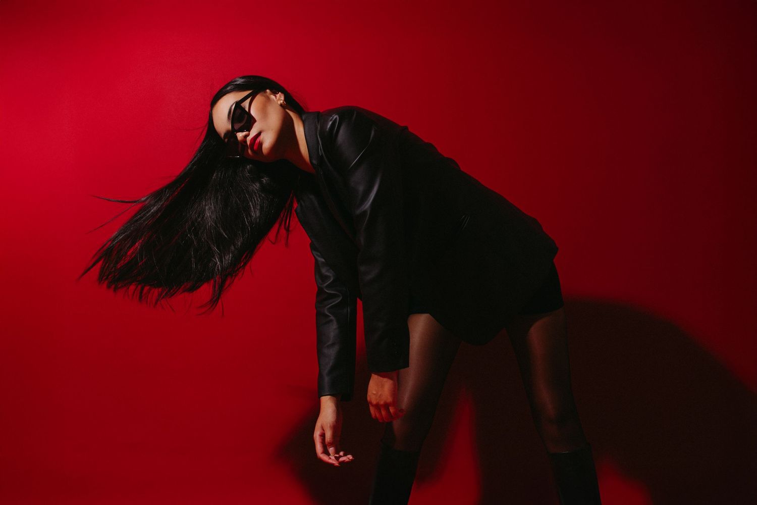 A silhouetted figure dances expressively against a dramatic red background creating an artistic performance silhouette.