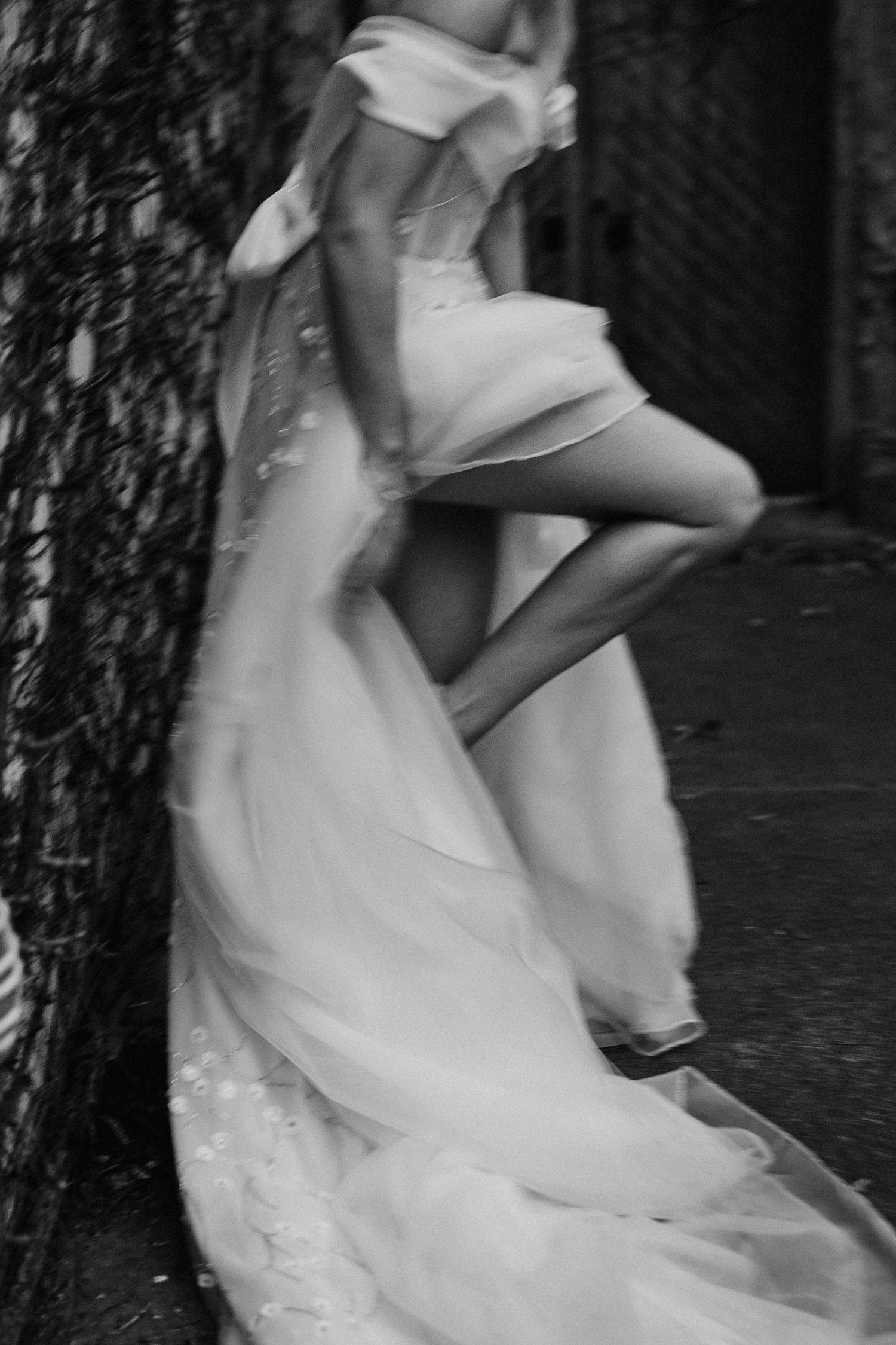 An artistic black and white photo showing the flowing movement of a wedding dress as someone spins in motion.
