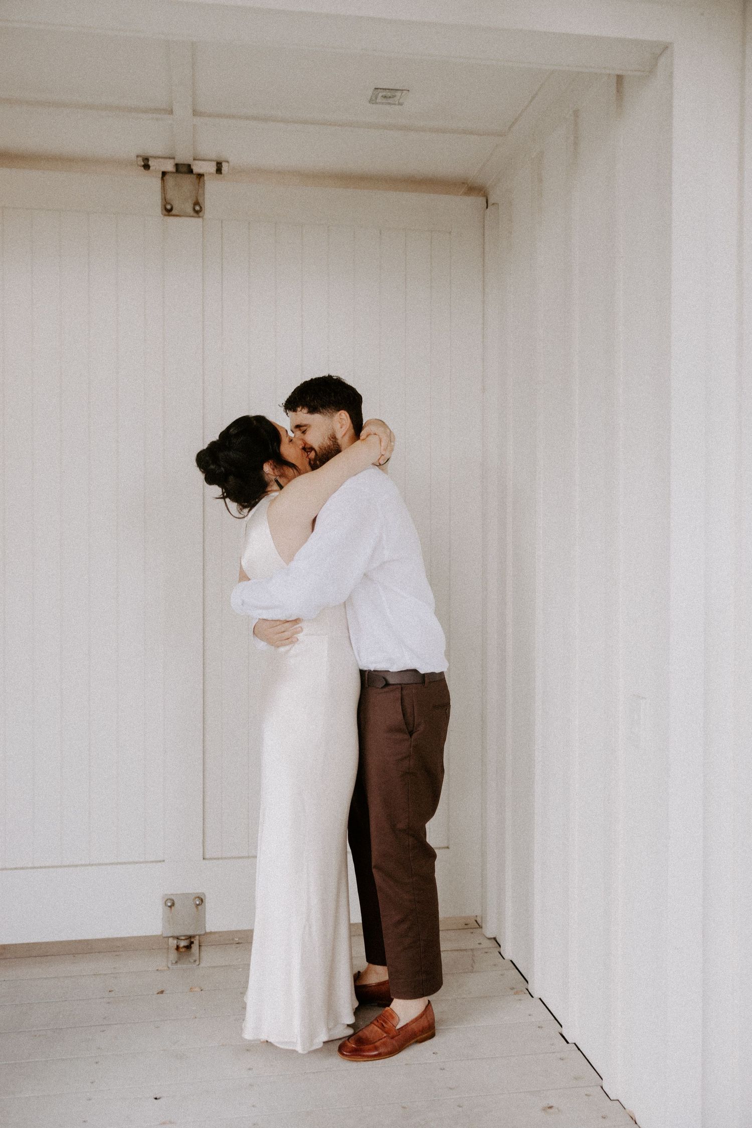 Couple dancing intimately in an elegant white room with simple decor.