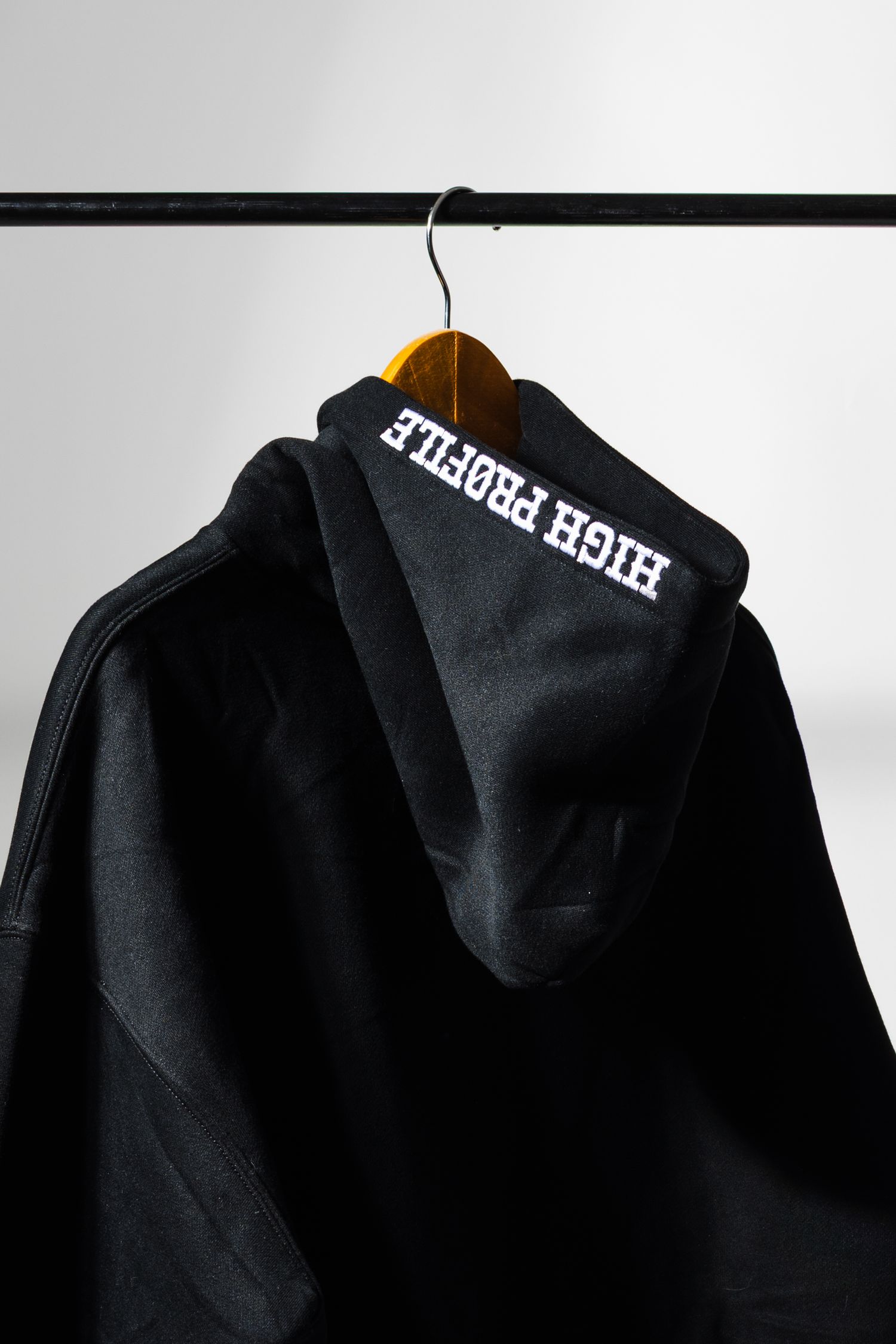 Black hooded sweatshirts hanging on clothing rack shown in retail display setting.