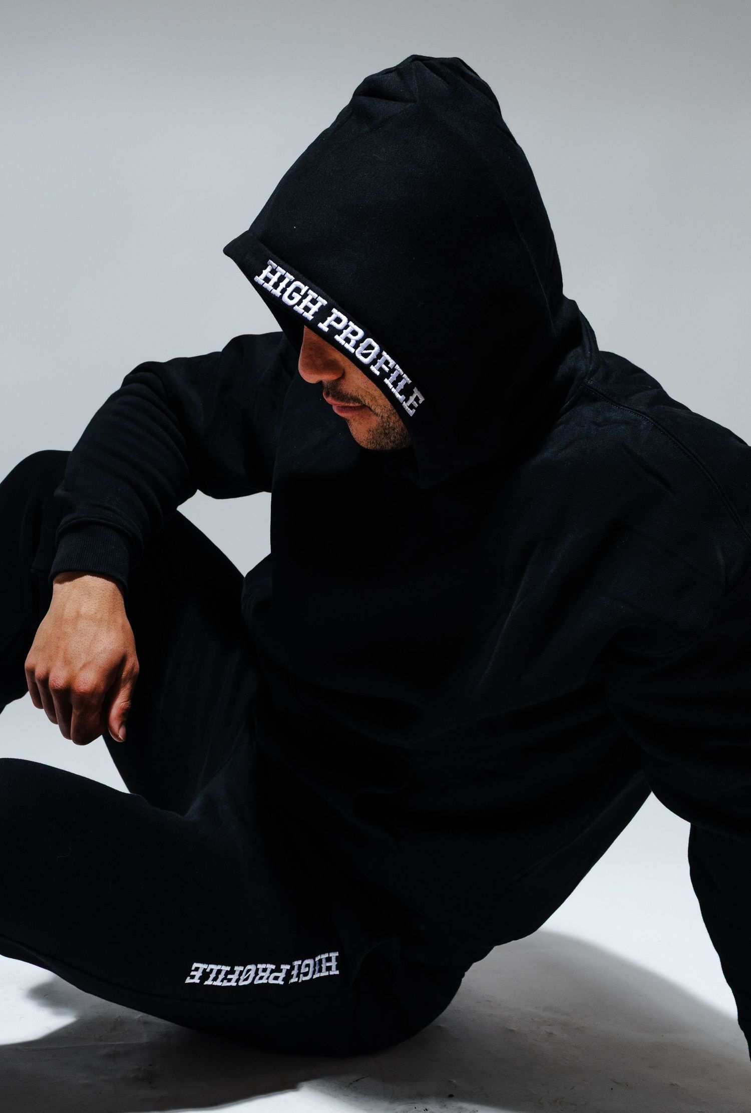 Person in black hoodie sweatshirt shown in dynamic fashion poses against light background.