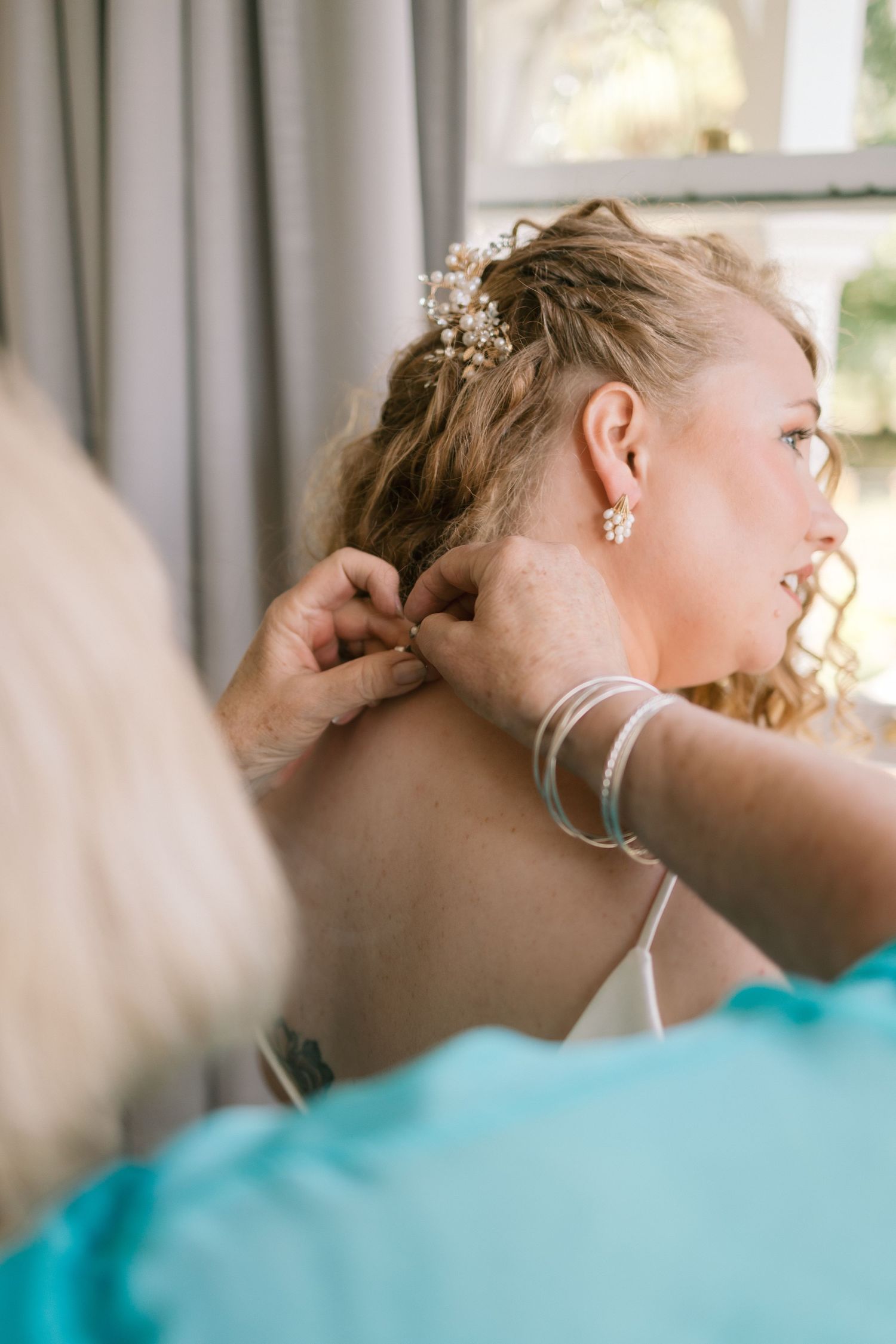 Getting ready scene with delicate floral hair accessories being pinned into blonde hair.