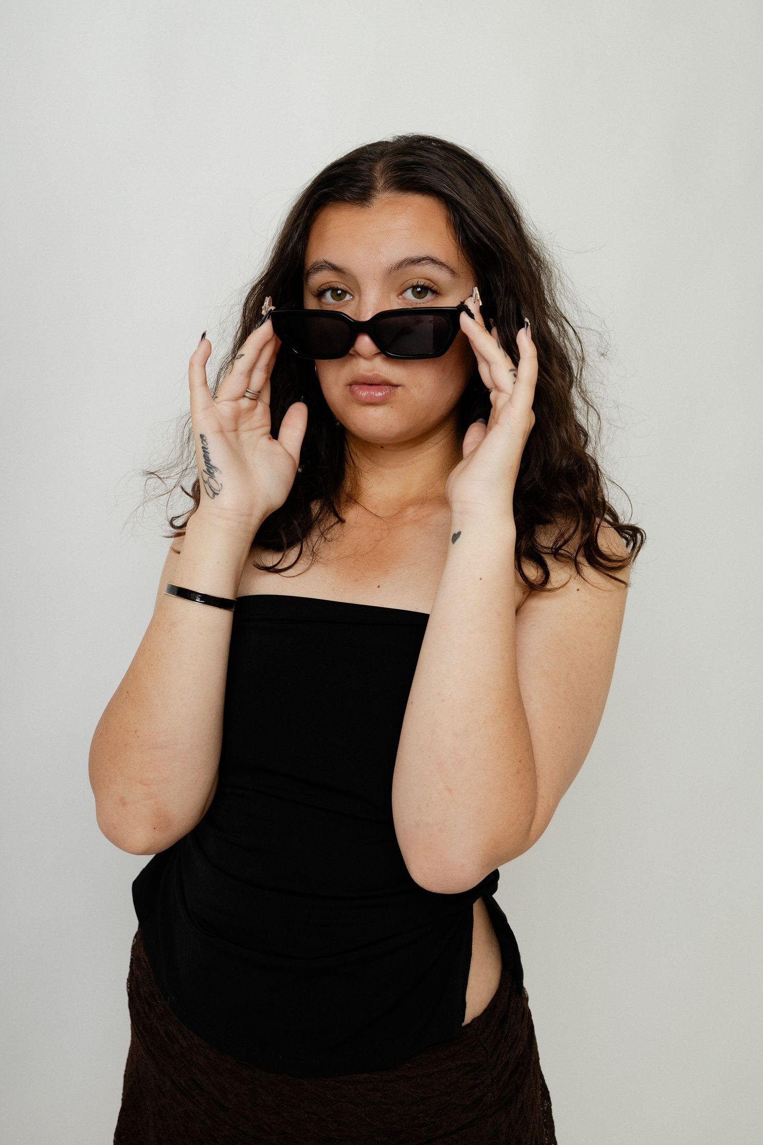 A series of four photos showing a person in a black top making expressive hand gestures against a light background.