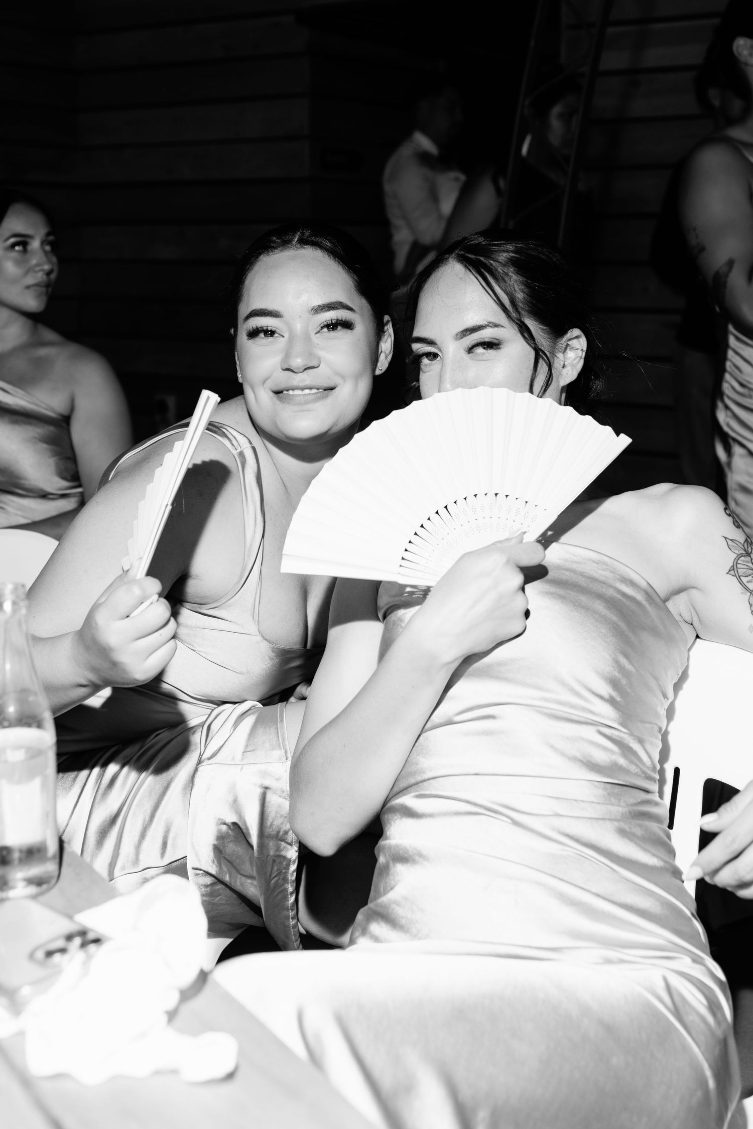 A black and white photo shows a group of people in white attire resting and lounging together.