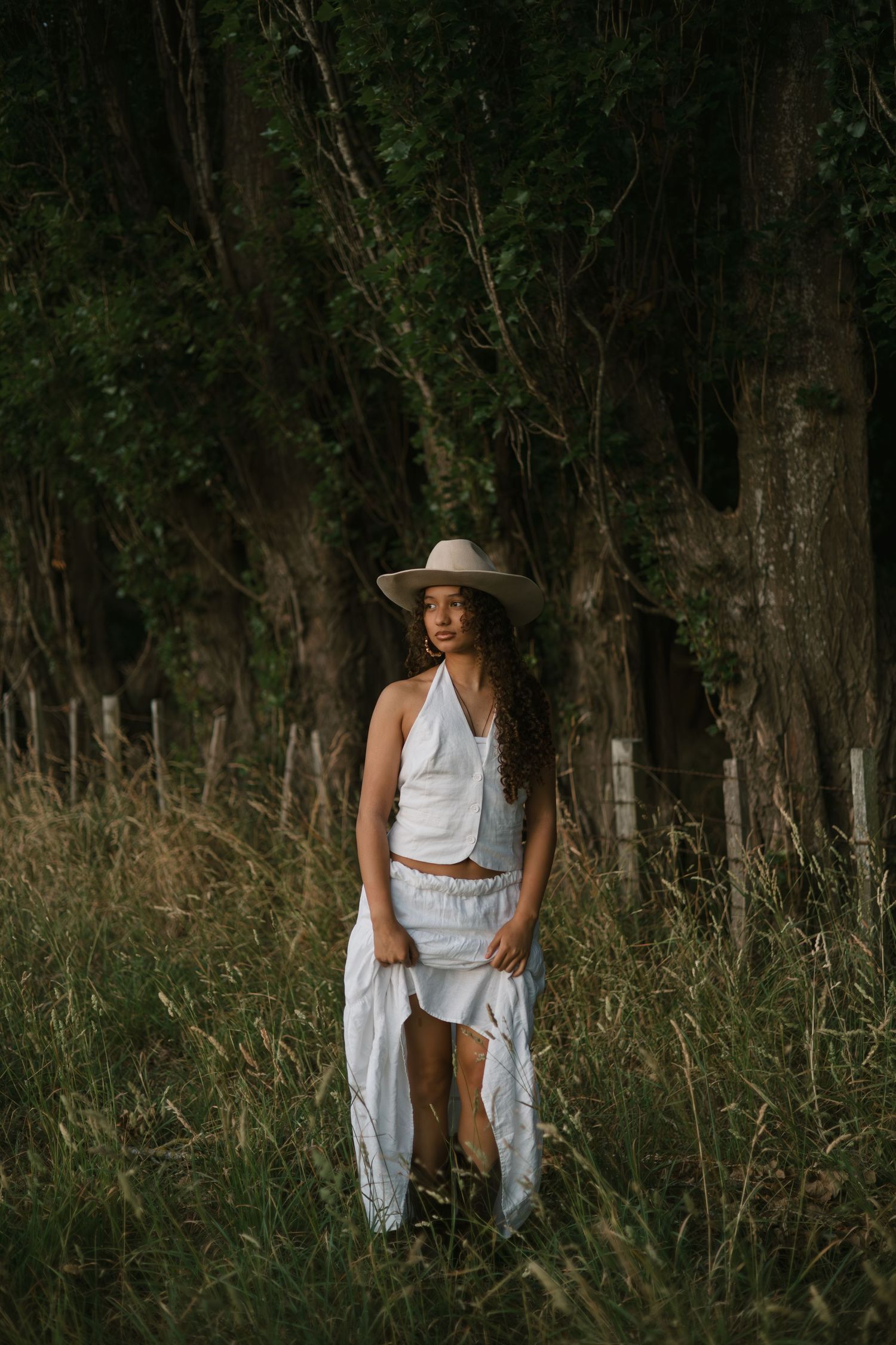 A series of moody outdoor portraits in a wooded setting with natural lighting and white summer clothing.