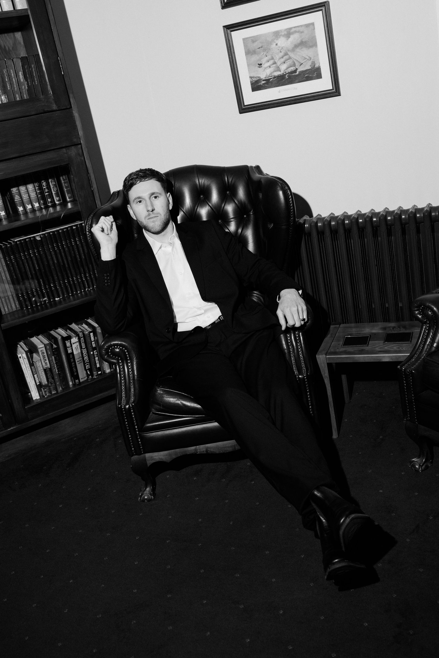 Black and white photo series showing formal poses in a study with leather furniture and bookshelves.