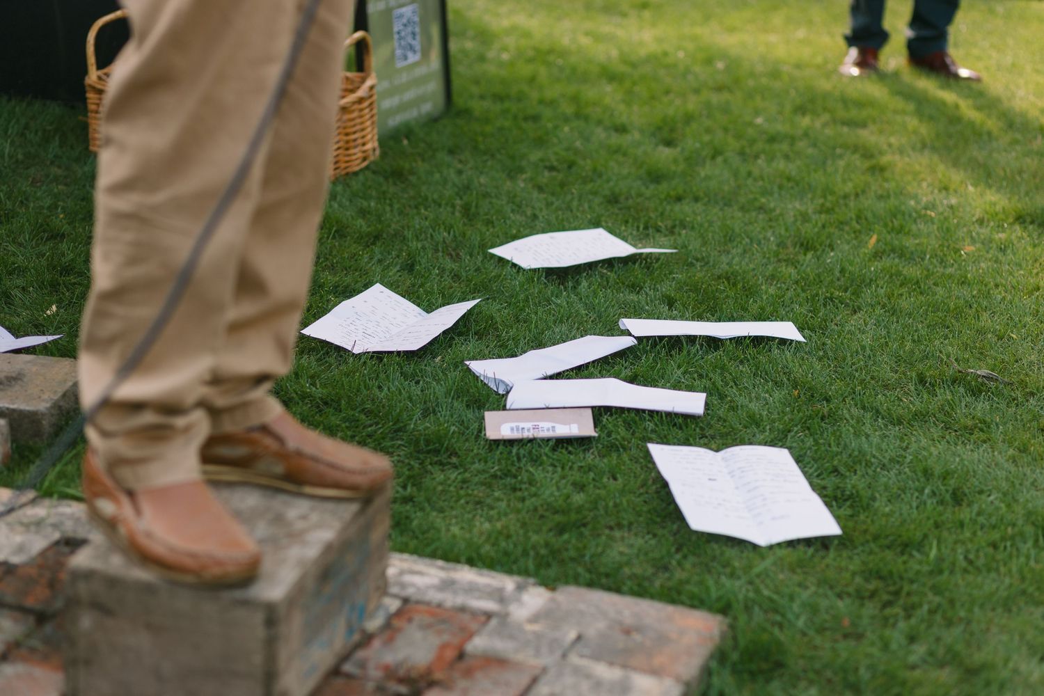 Papers scattered on grass with boots visible during an outdoor event.