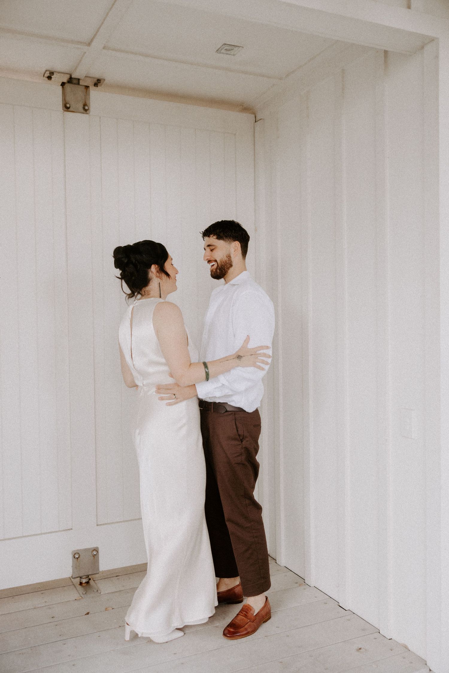 Couple posing against white walls in an intimate indoor photoshoot series.