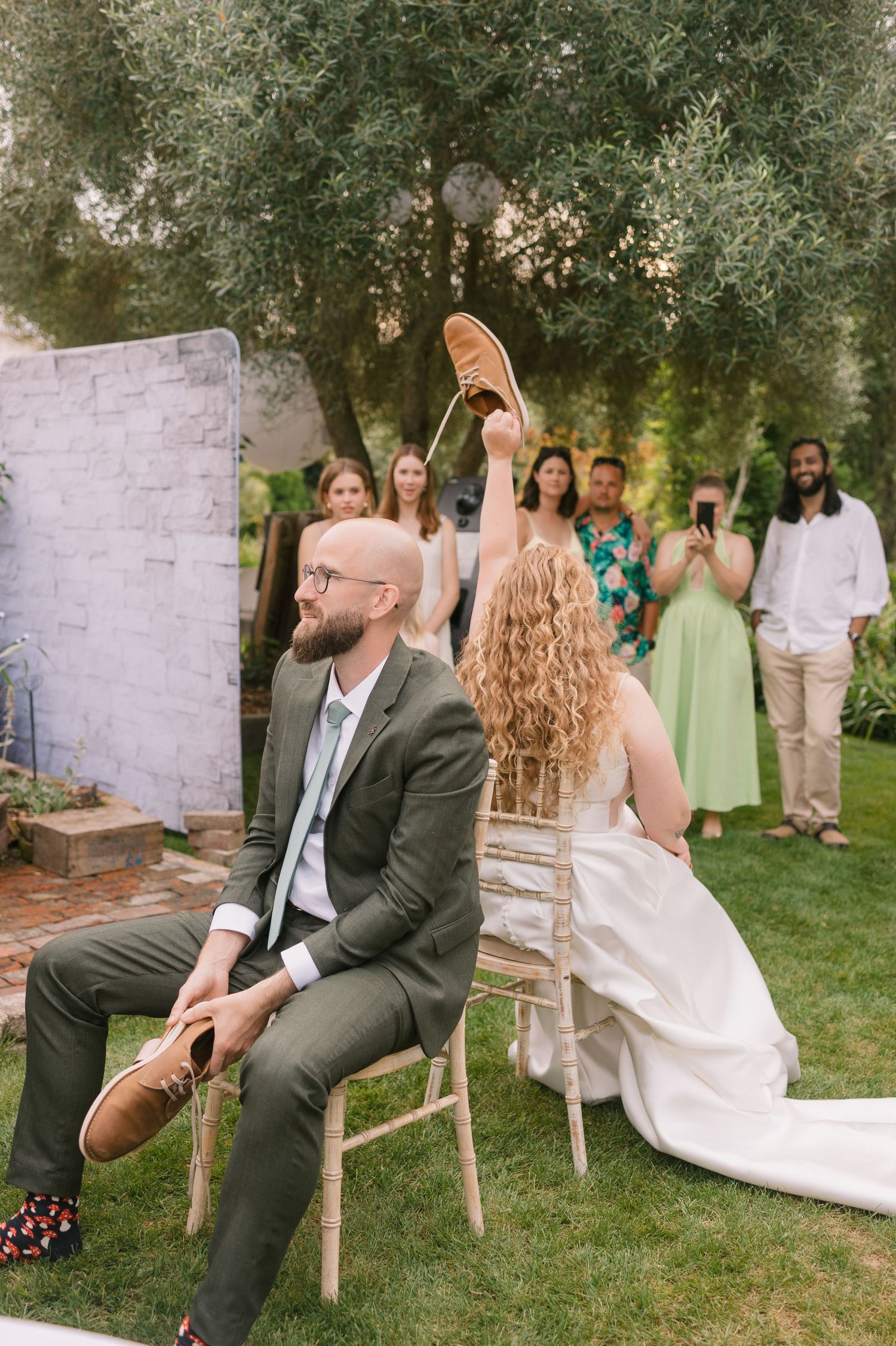 Outdoor game of musical chairs being played at a garden wedding reception.