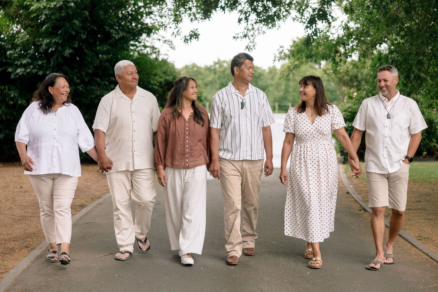 A group walking together in white and beige clothing along a path during a sunny day outdoors.
