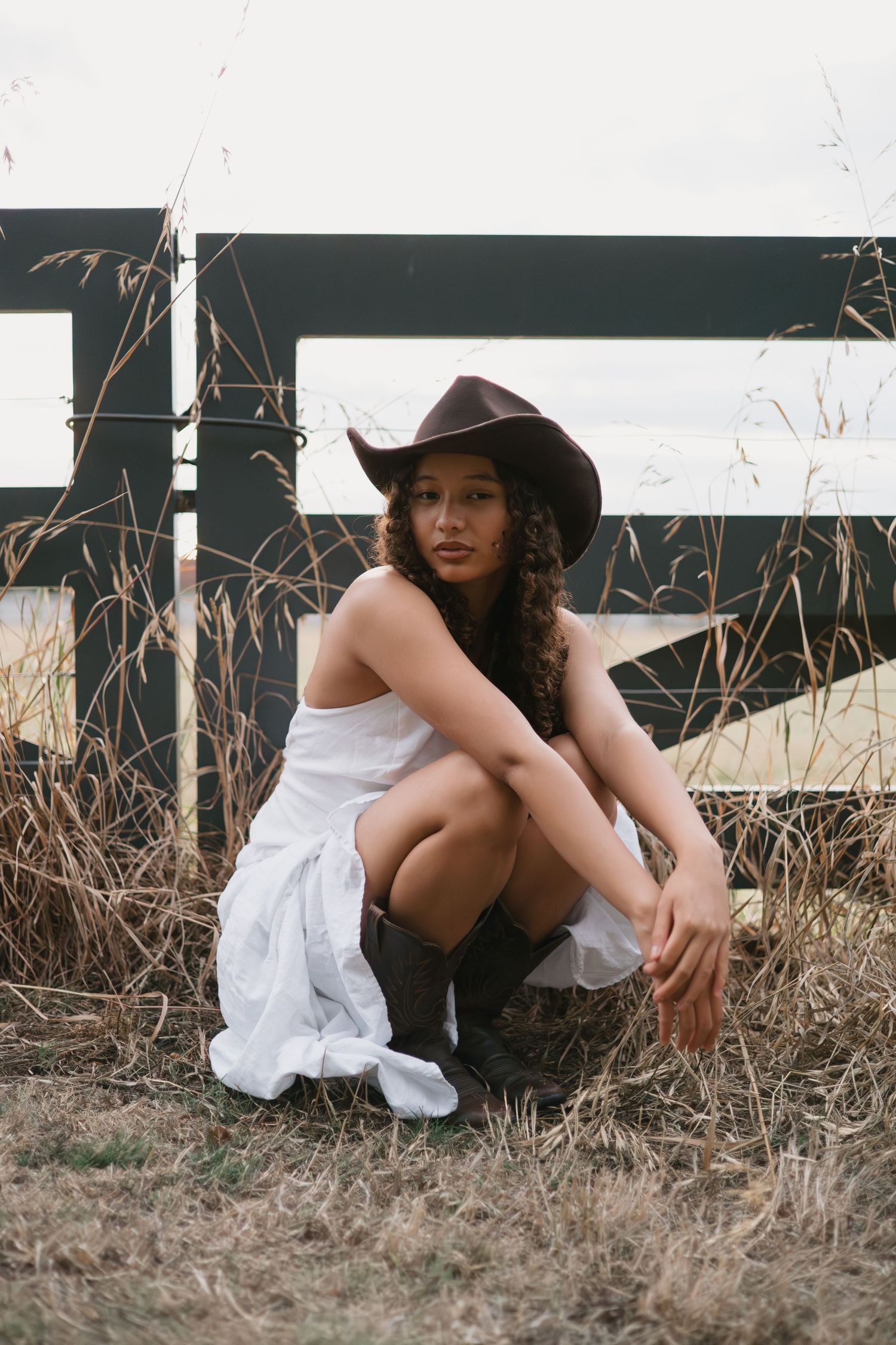 Artistic portraits taken against a dark background with dried grass and white clothing details.