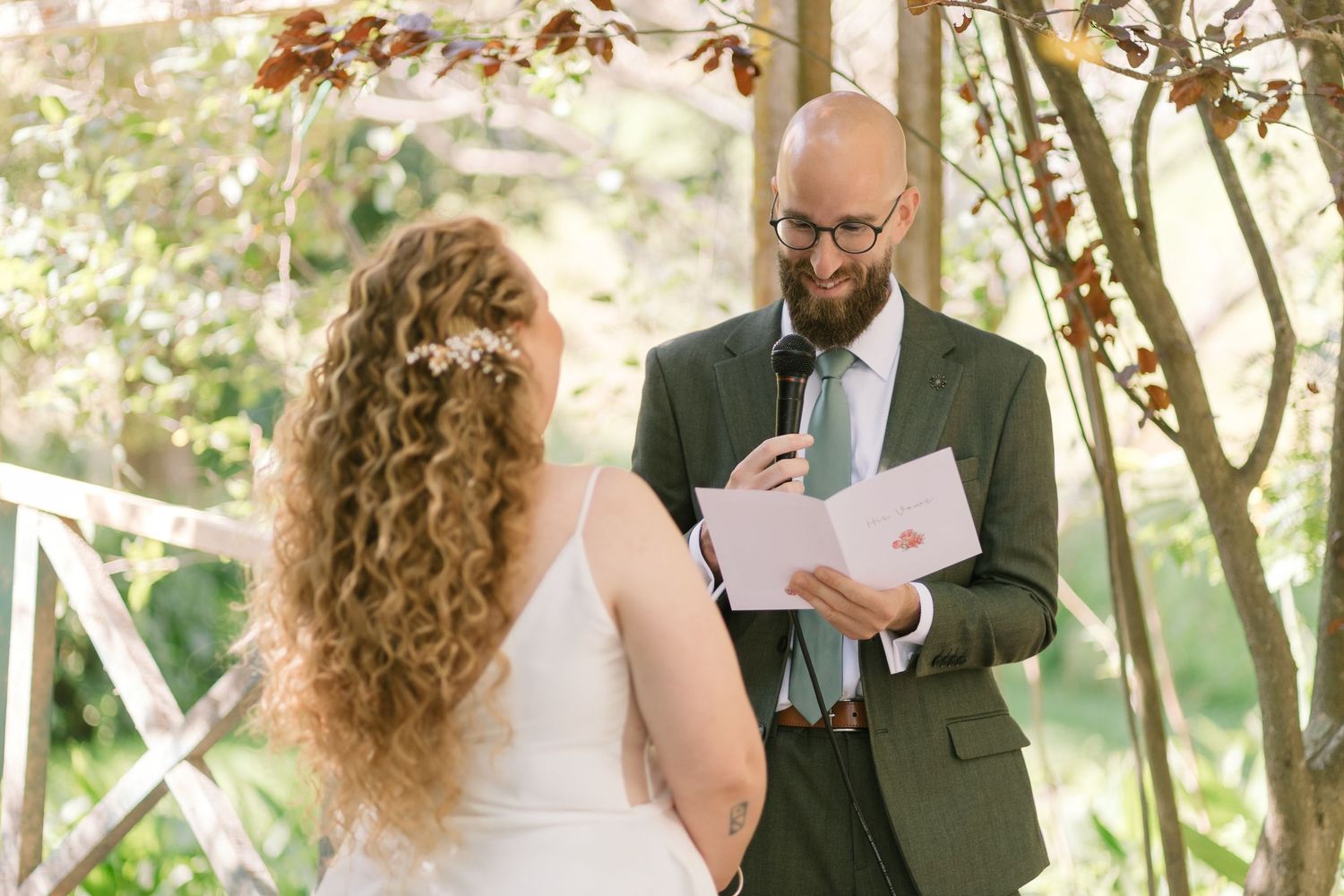 An outdoor wedding ceremony under autumn foliage with a couple exchanging vows.