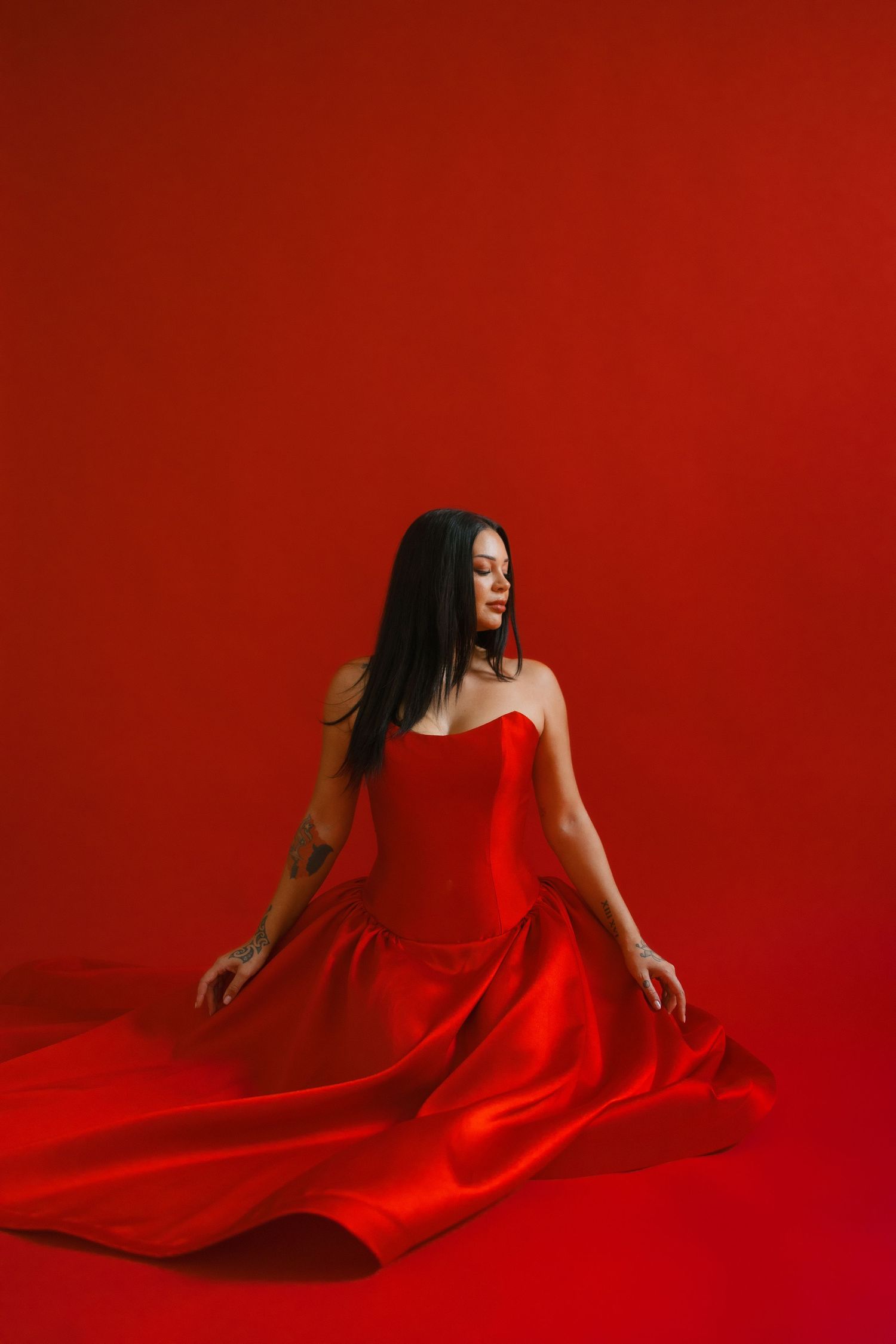A figure in a flowing red dress creates dramatic poses against a vivid crimson background in a stylized fashion photo series.