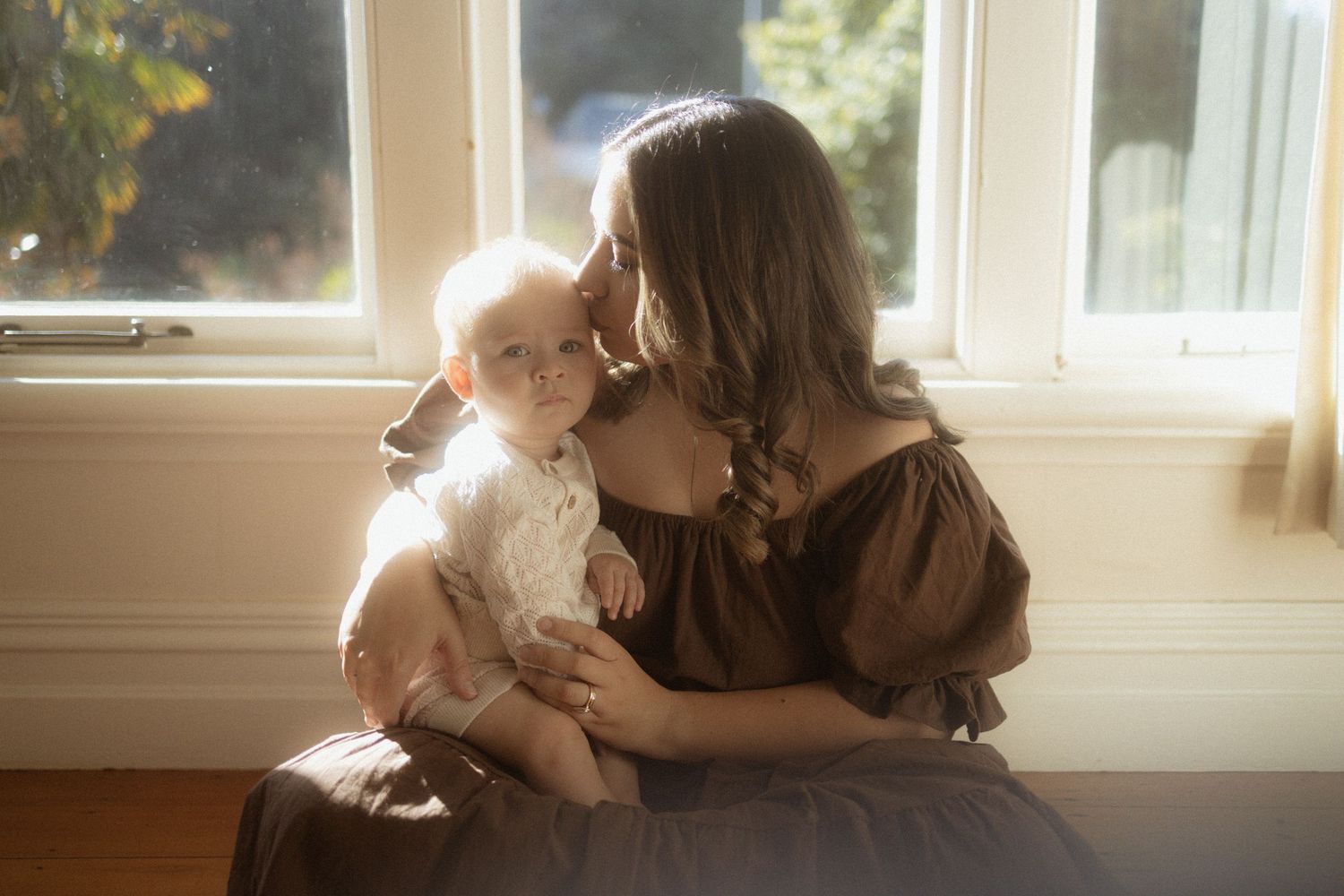 A tender moment by a window with soft natural light streaming in, creating a warm and intimate atmosphere.