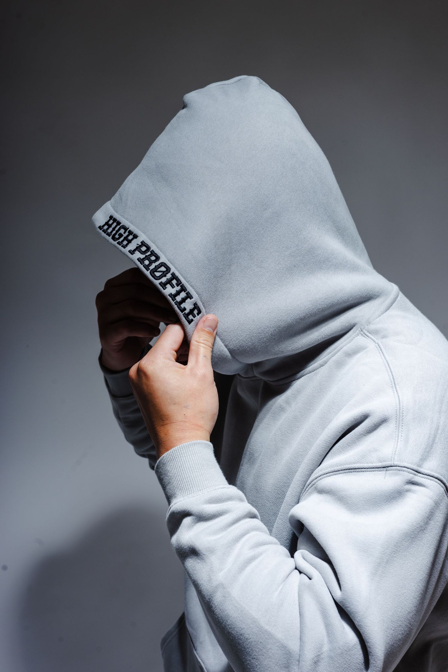 Sequence showing hoodie being pulled up and adjusted on a figure against a gray gradient background.