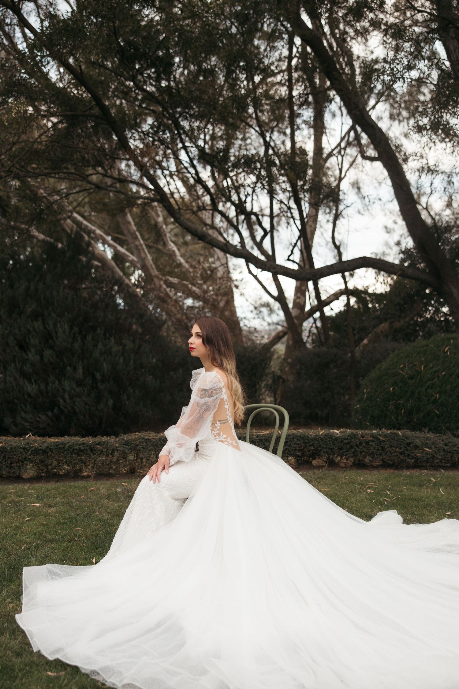 An elegant wedding dress with long sleeves and flowing white tulle skirt photographed in a garden setting.