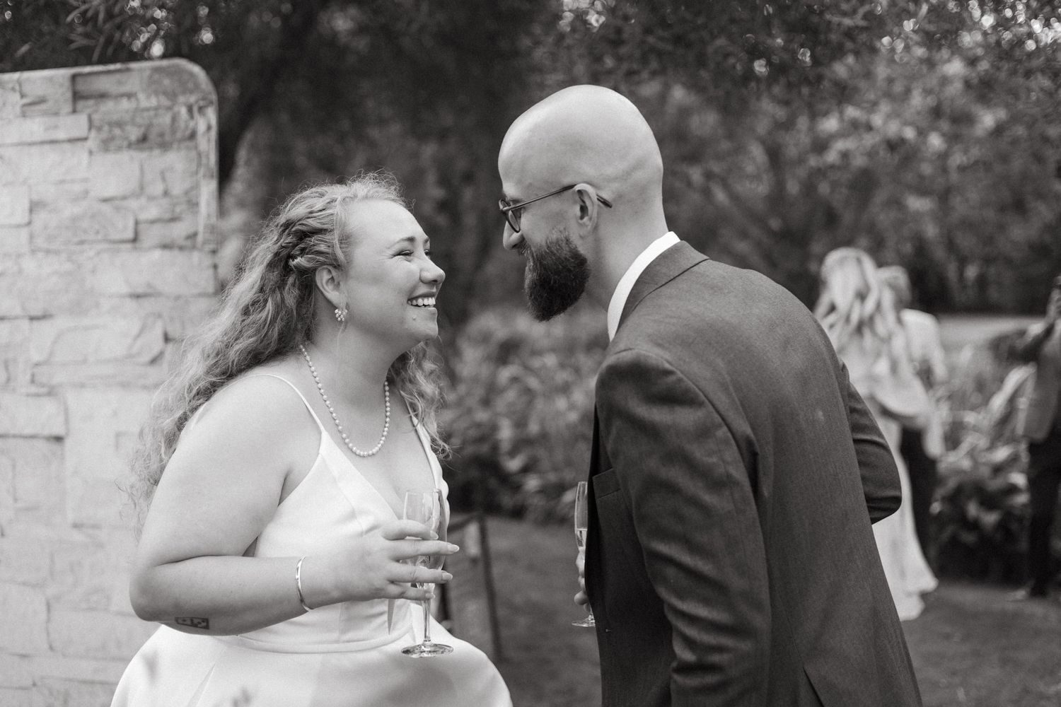 Black and white wedding moment captured against stone wall background.