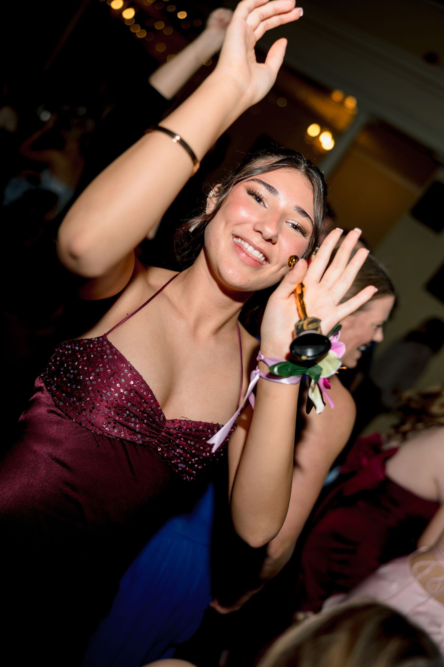 Young woman in burgundy dress dancing and smiling at a formal party event.