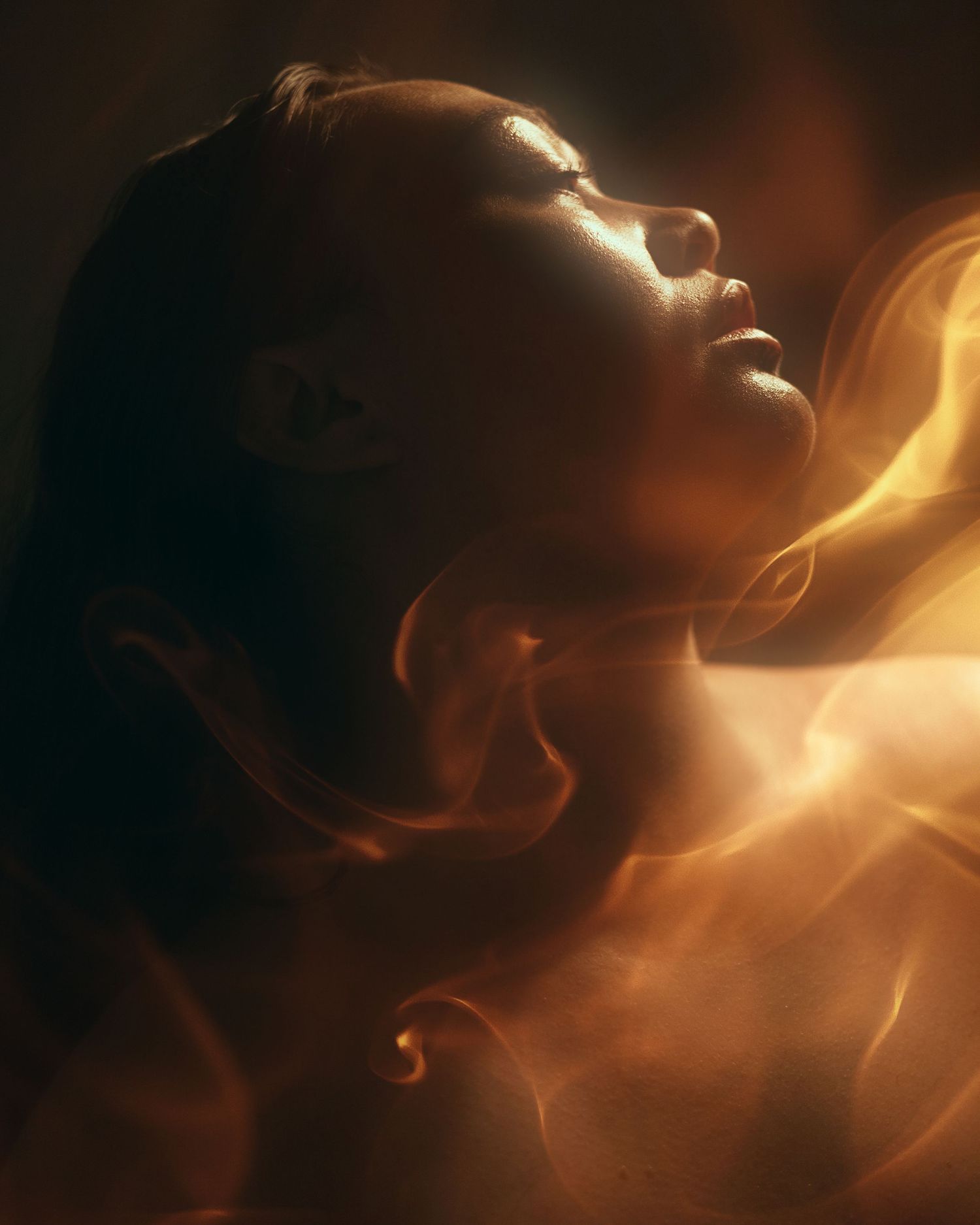 A dramatic portrait in warm amber lighting with swirling smoke effects creating an ethereal atmosphere.