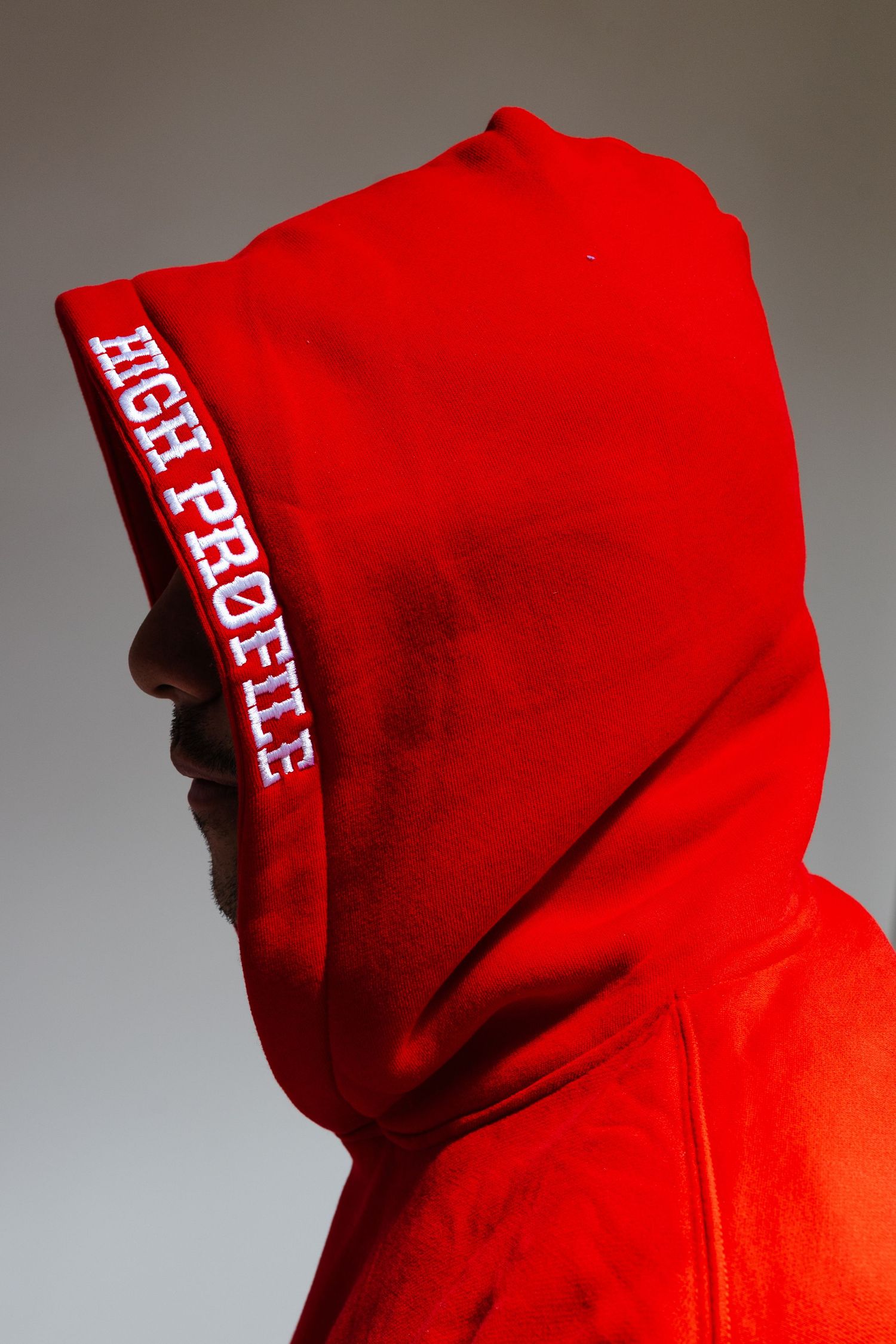 Red hoodie sweatshirt details showing white text printing against vibrant red fabric background.