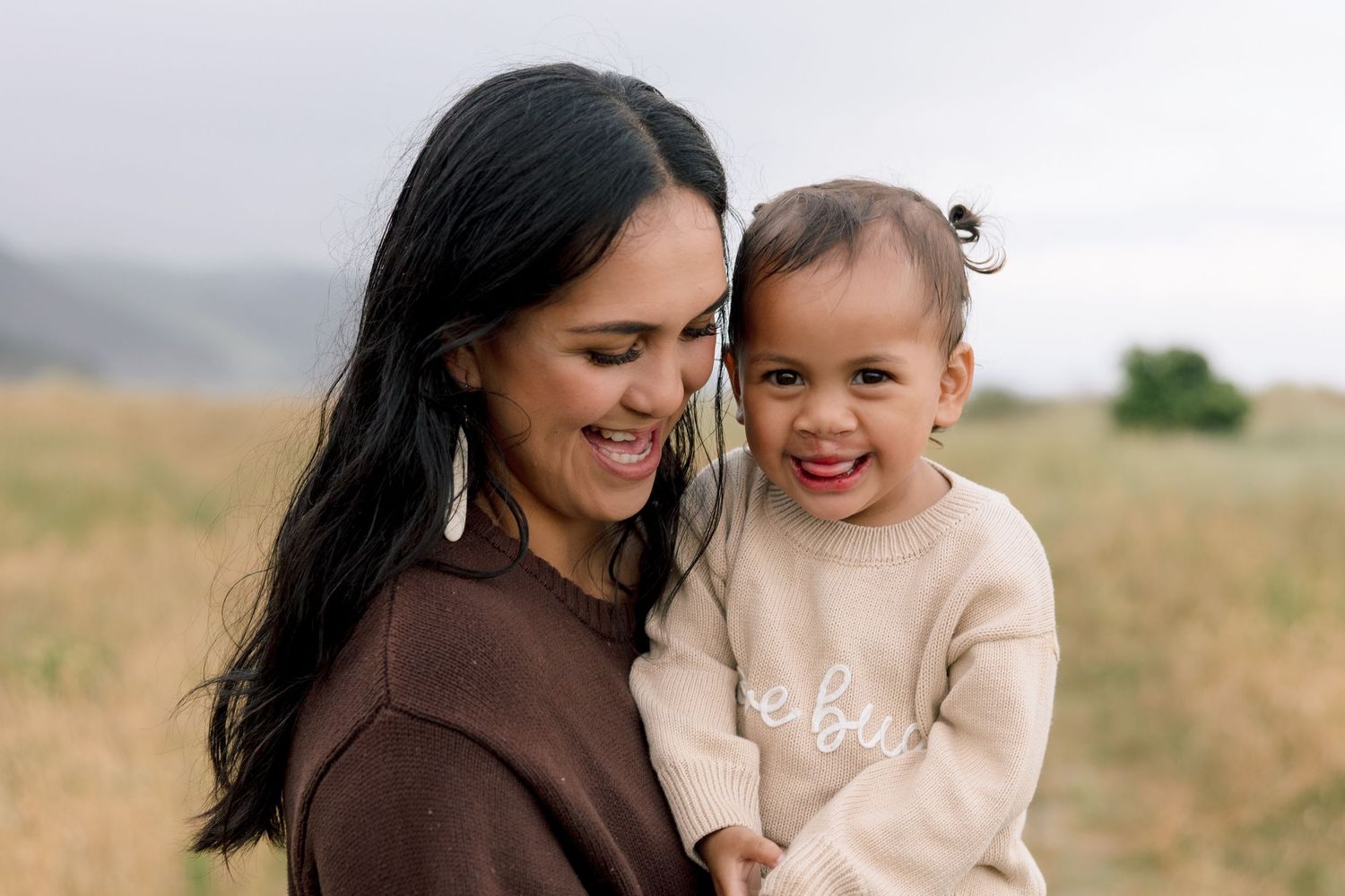 Parent and child share a joyful moment together outdoors in a natural setting during golden hour.