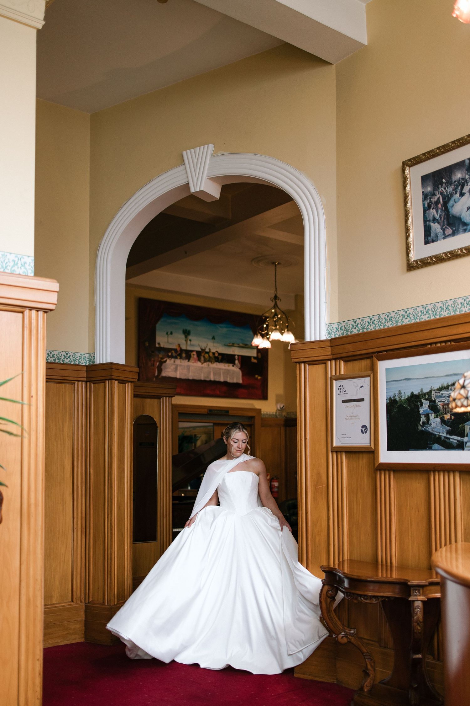A panoramic sequence of a white wedding dress twirling in an elegant wood-paneled hallway with classical columns.