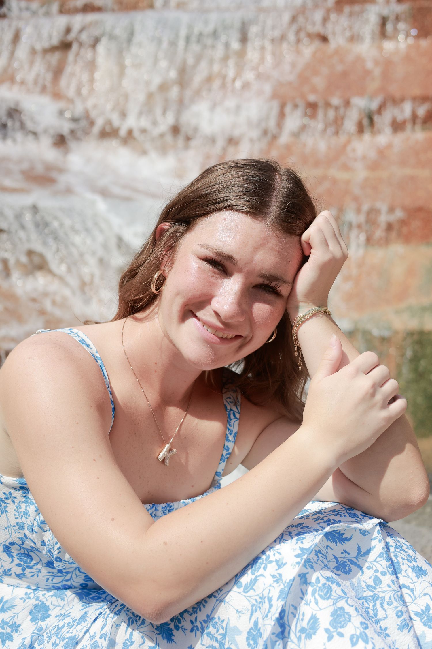 A series of four photos showing someone in a blue and white floral dress laying on a brick wall background.