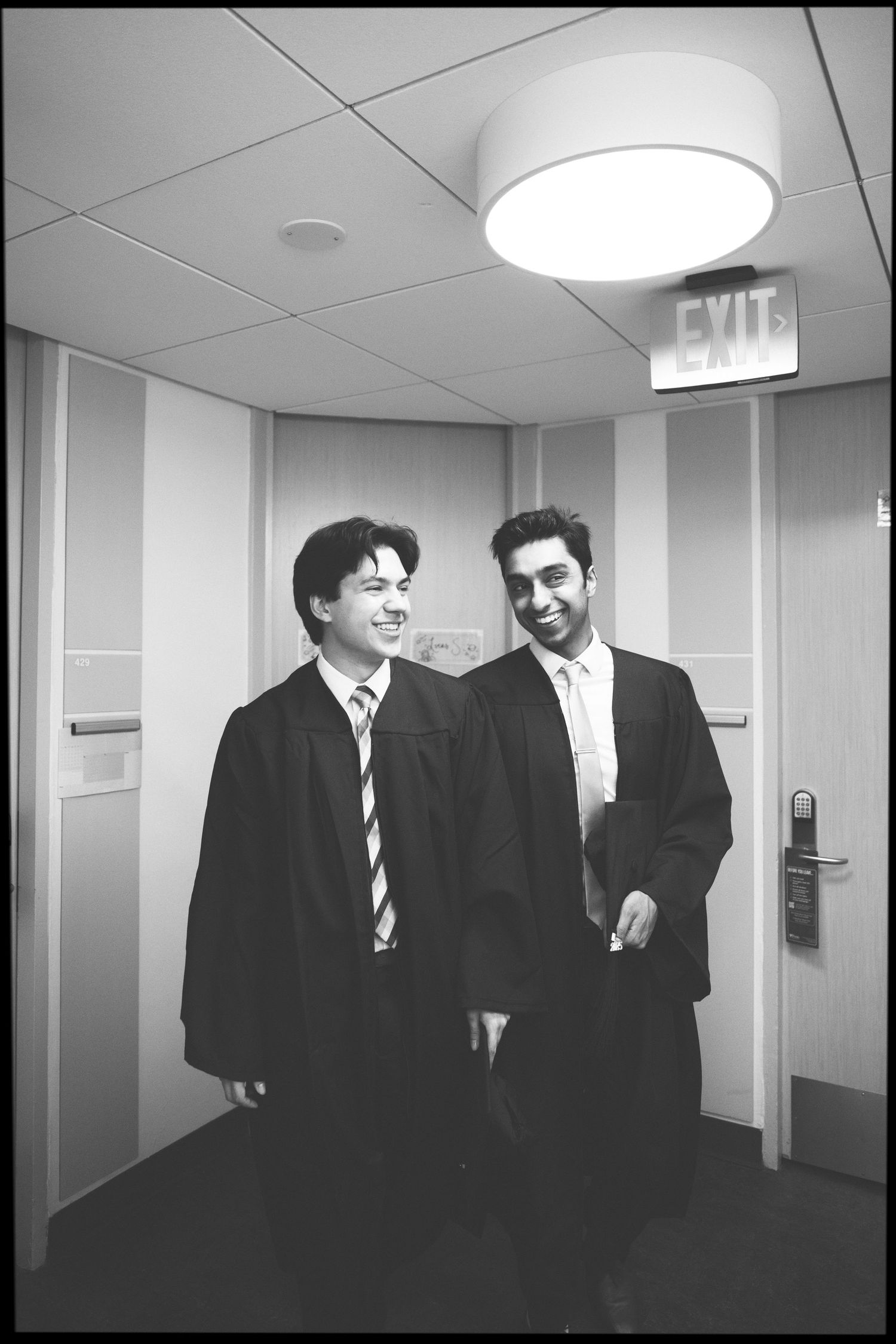 Black and white hallway photoshoot featuring graduates in formal attire.