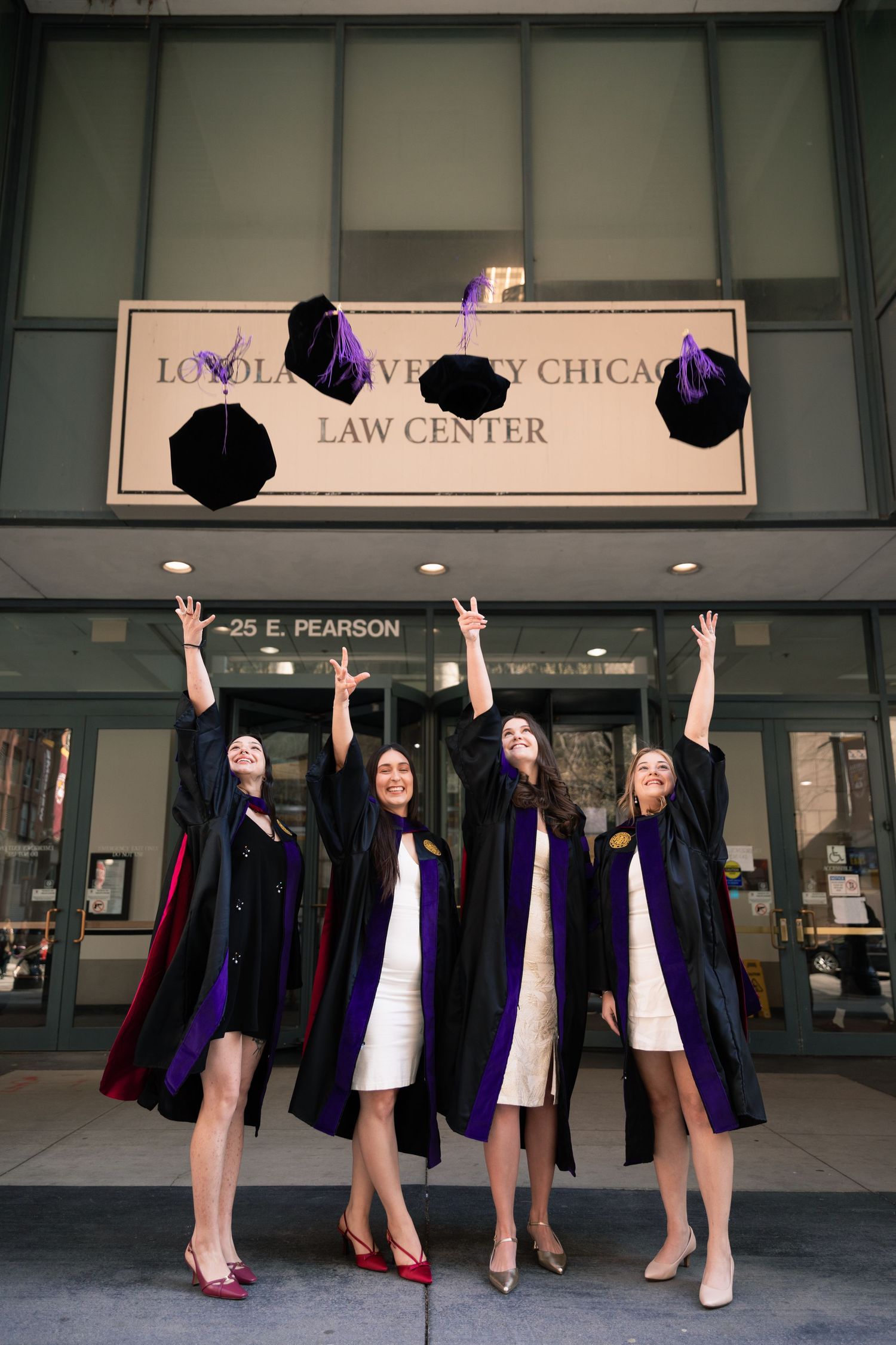 Law school graduates celebrating outside the Law Center building with raised arms.