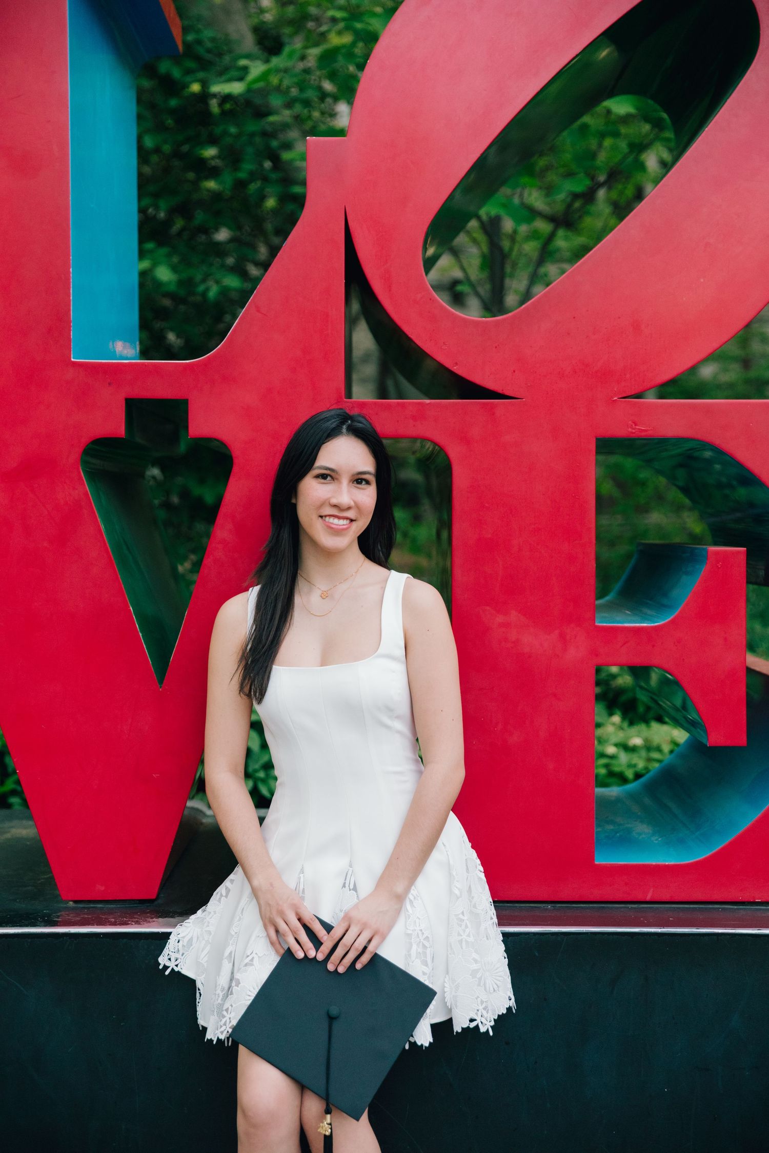 A graduation photo shoot in front of large red LOVE letters outdoors.