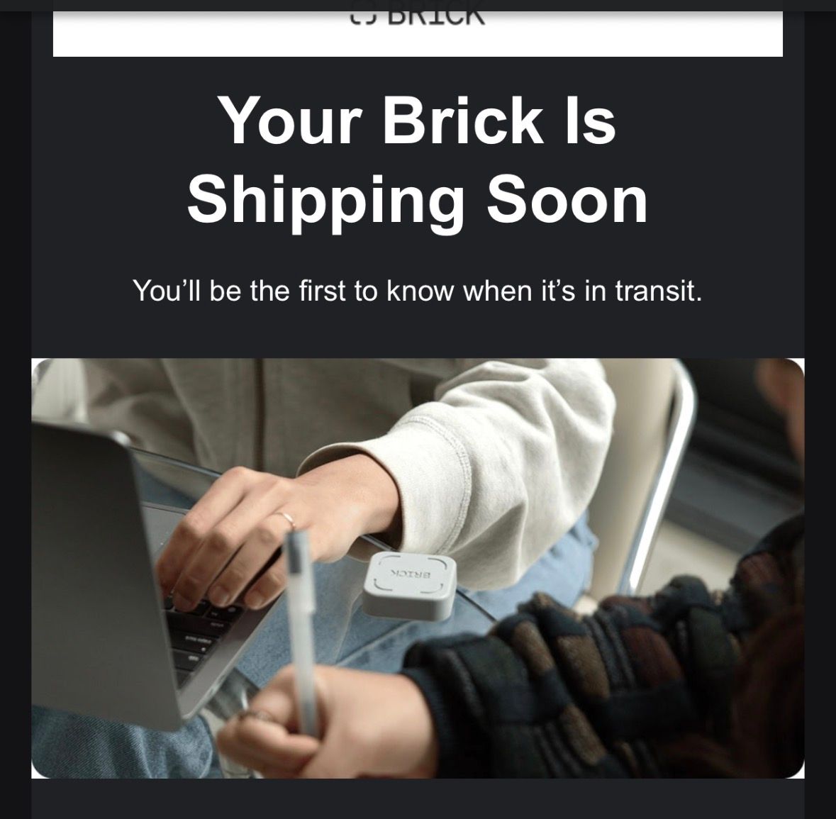 Email notification showing Your Brick Is Shipping Soon message with person using laptop and stylus in background.
