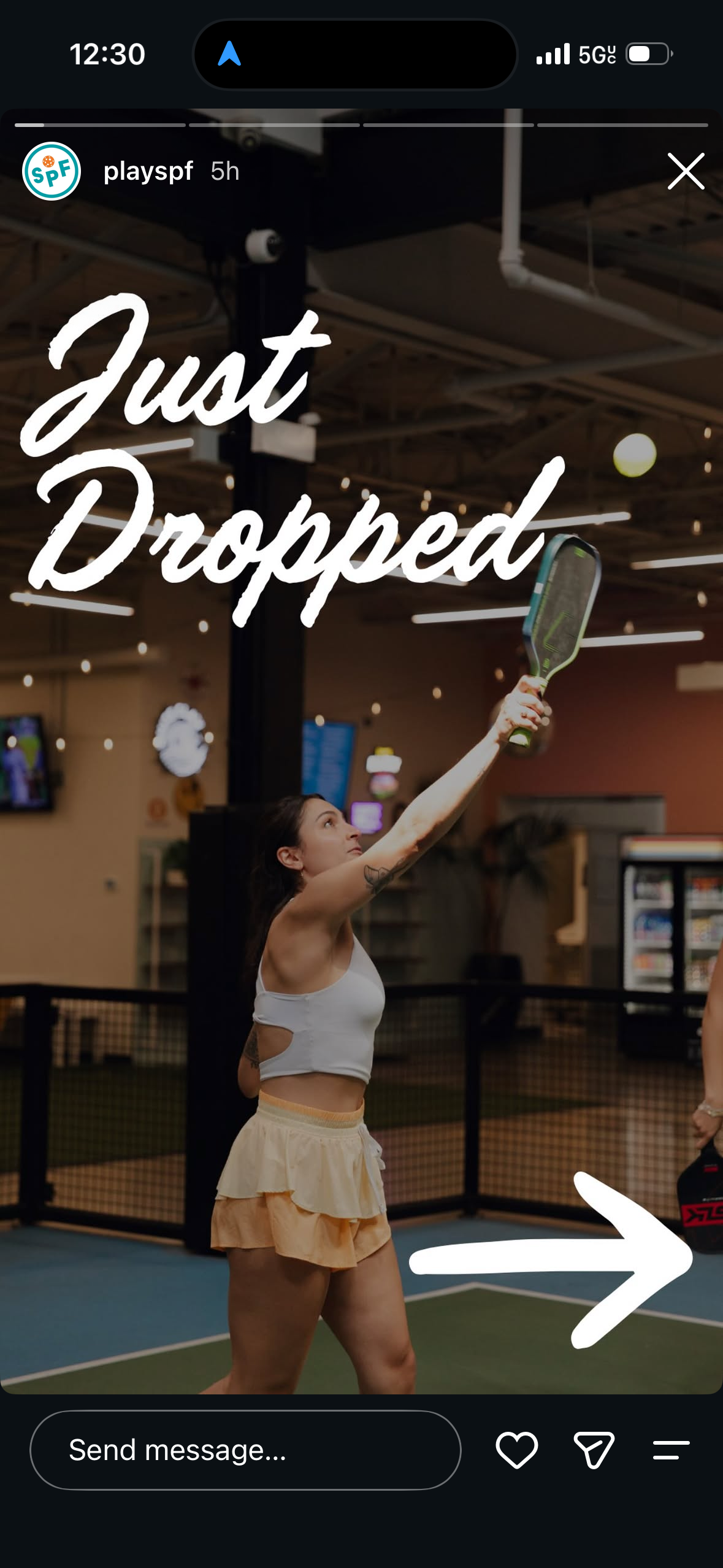 Woman playing pickleball indoors, reaching up to hit ball with paddle, wearing white top and yellow skirt.