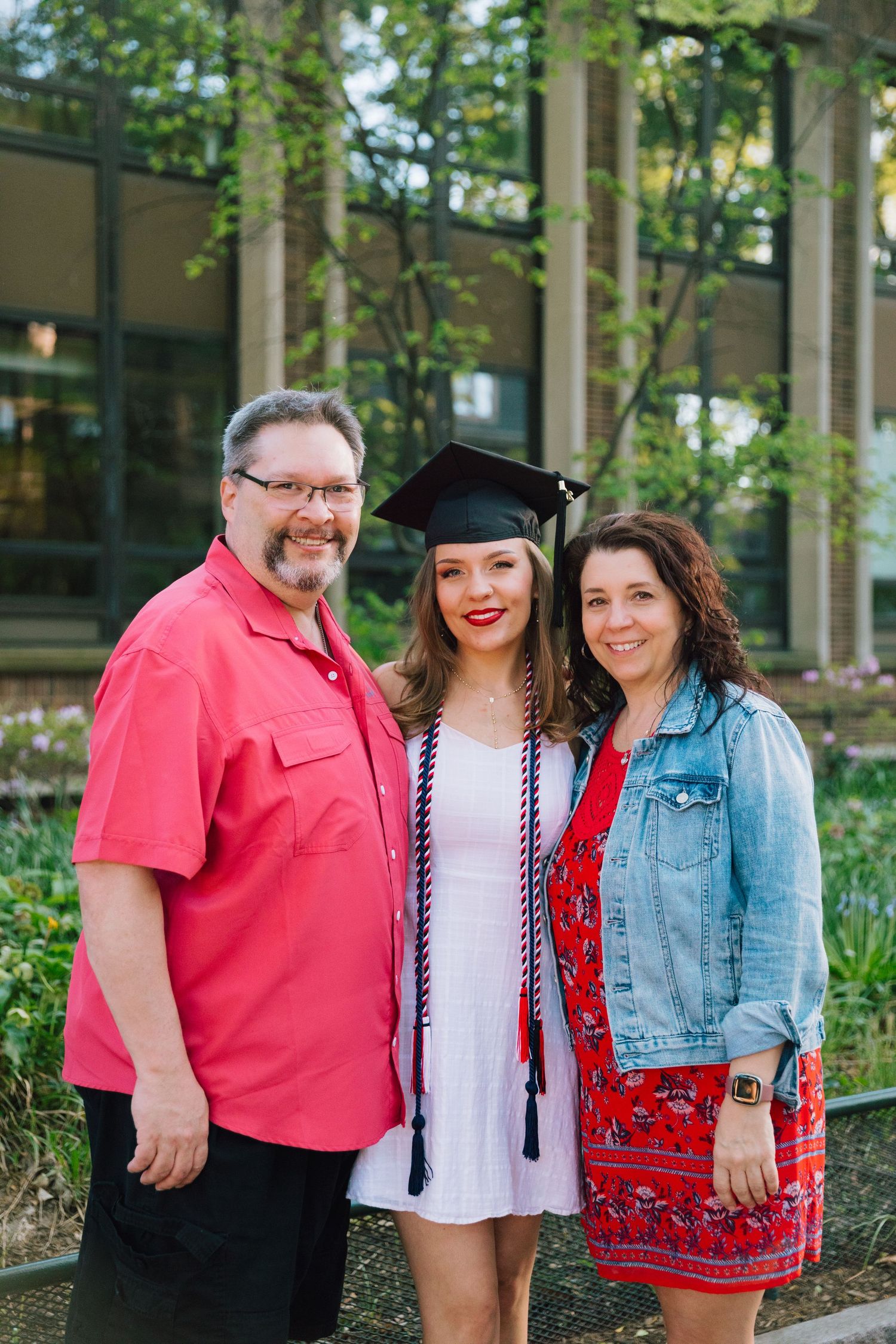Family poses together outdoors during graduation celebration.