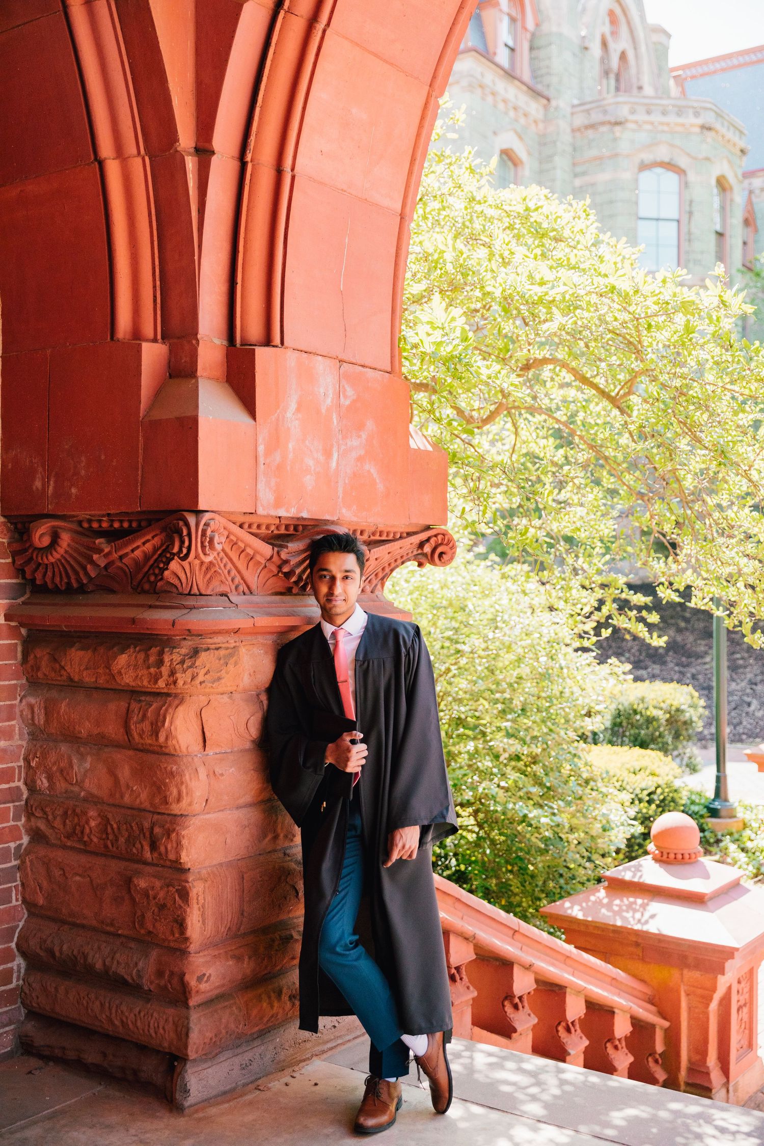 Professional graduation photos taken under red brick archway in natural lighting.