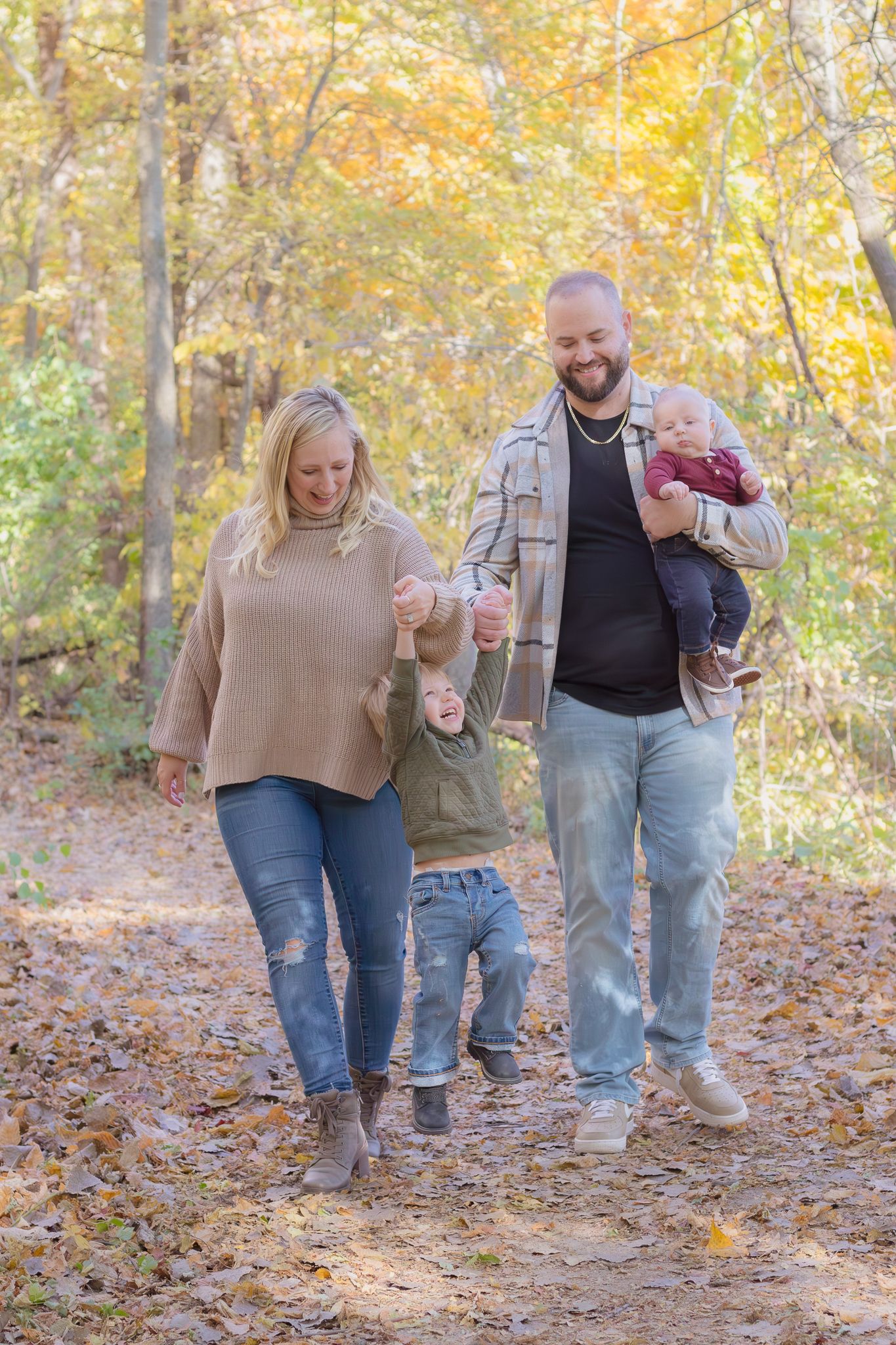 Group walking through autumn woods covered in fallen leaves on a sunny day.