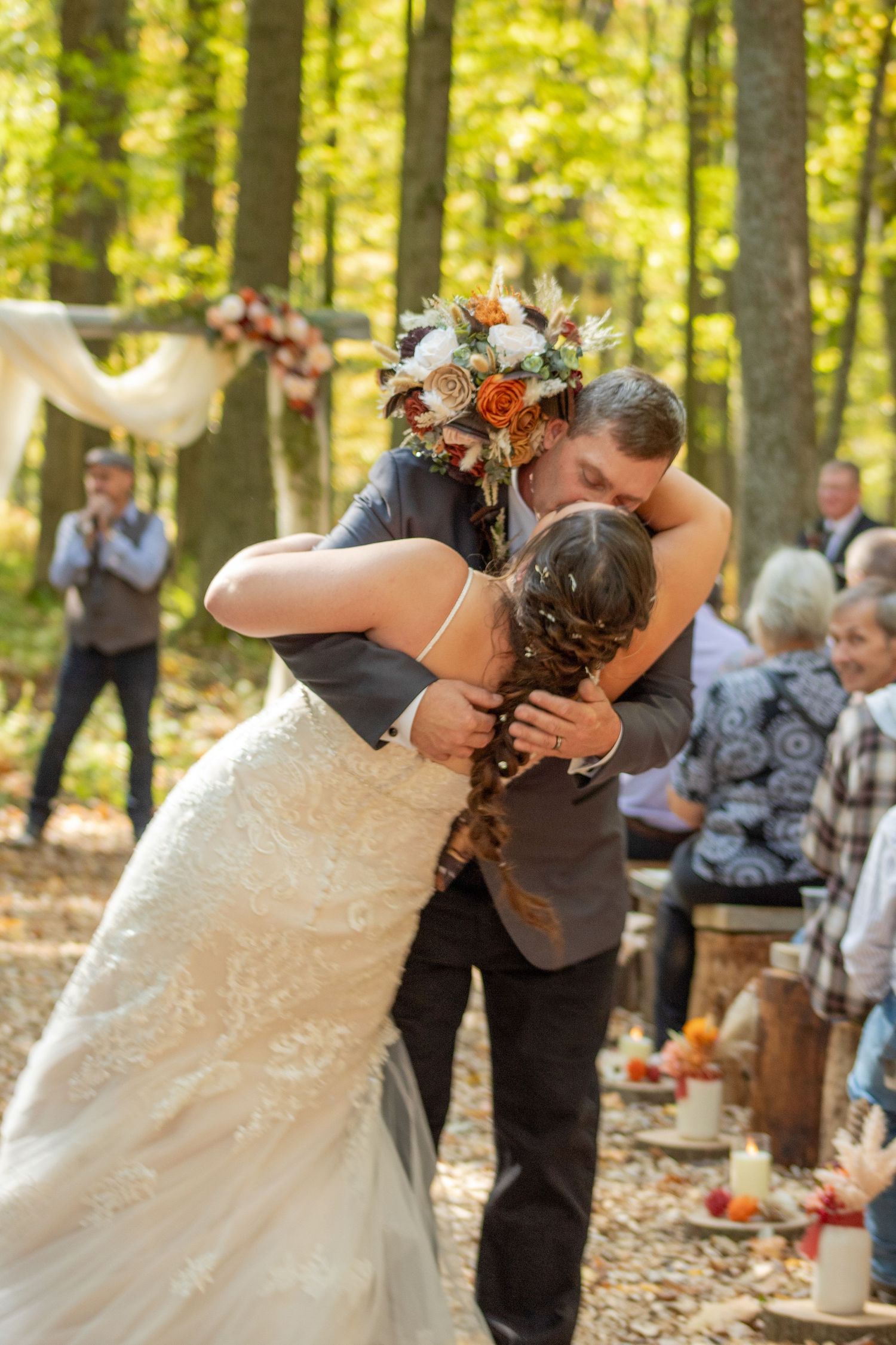 Wedding couple sharing an intimate moment during their forest ceremony surrounded by fall foliage.