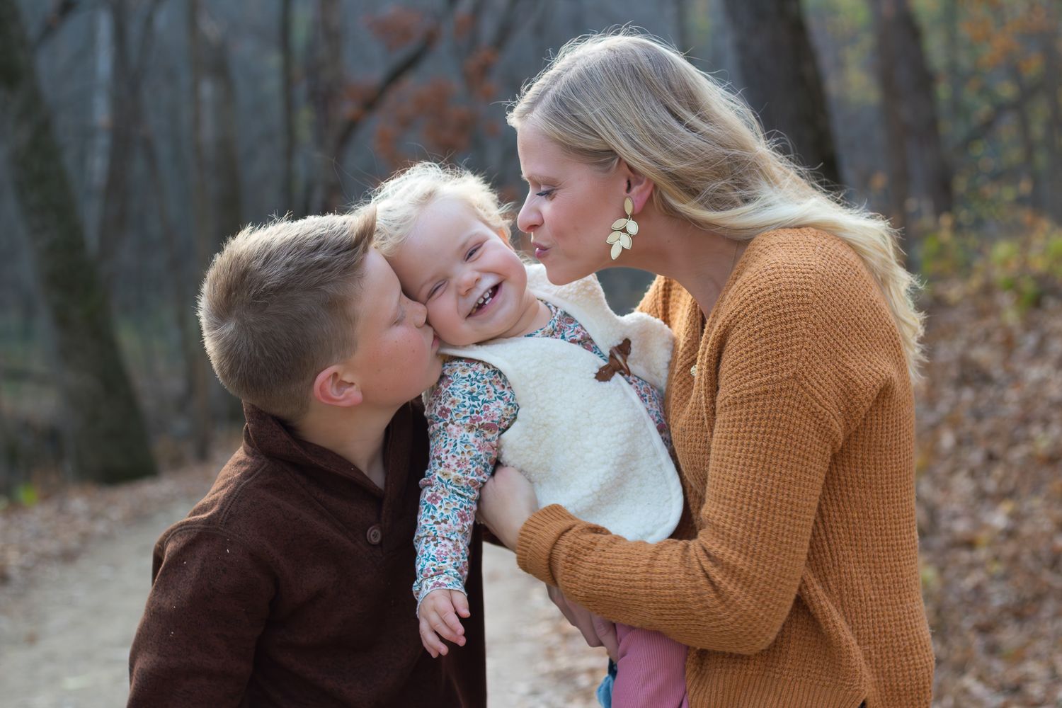 A tender moment of laughter and affection shared on a forest path.