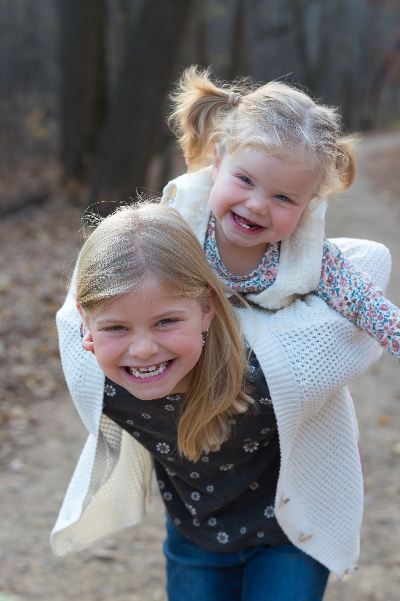 Two children in sweaters playing and laughing together outdoors in autumn.